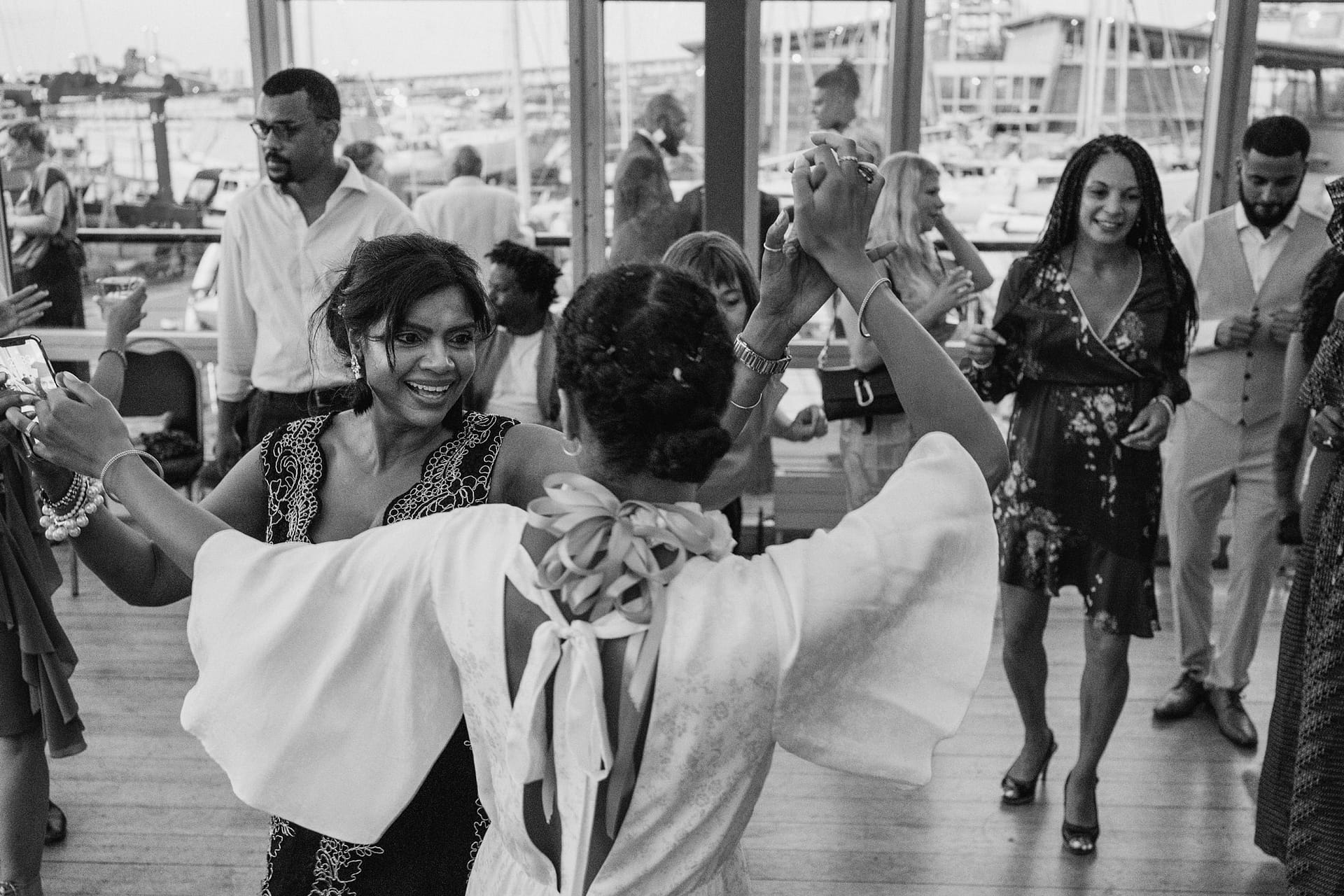 A black and white photo capturing the elegance and joy of people dancing at a Greenwich Yacht Club wedding.