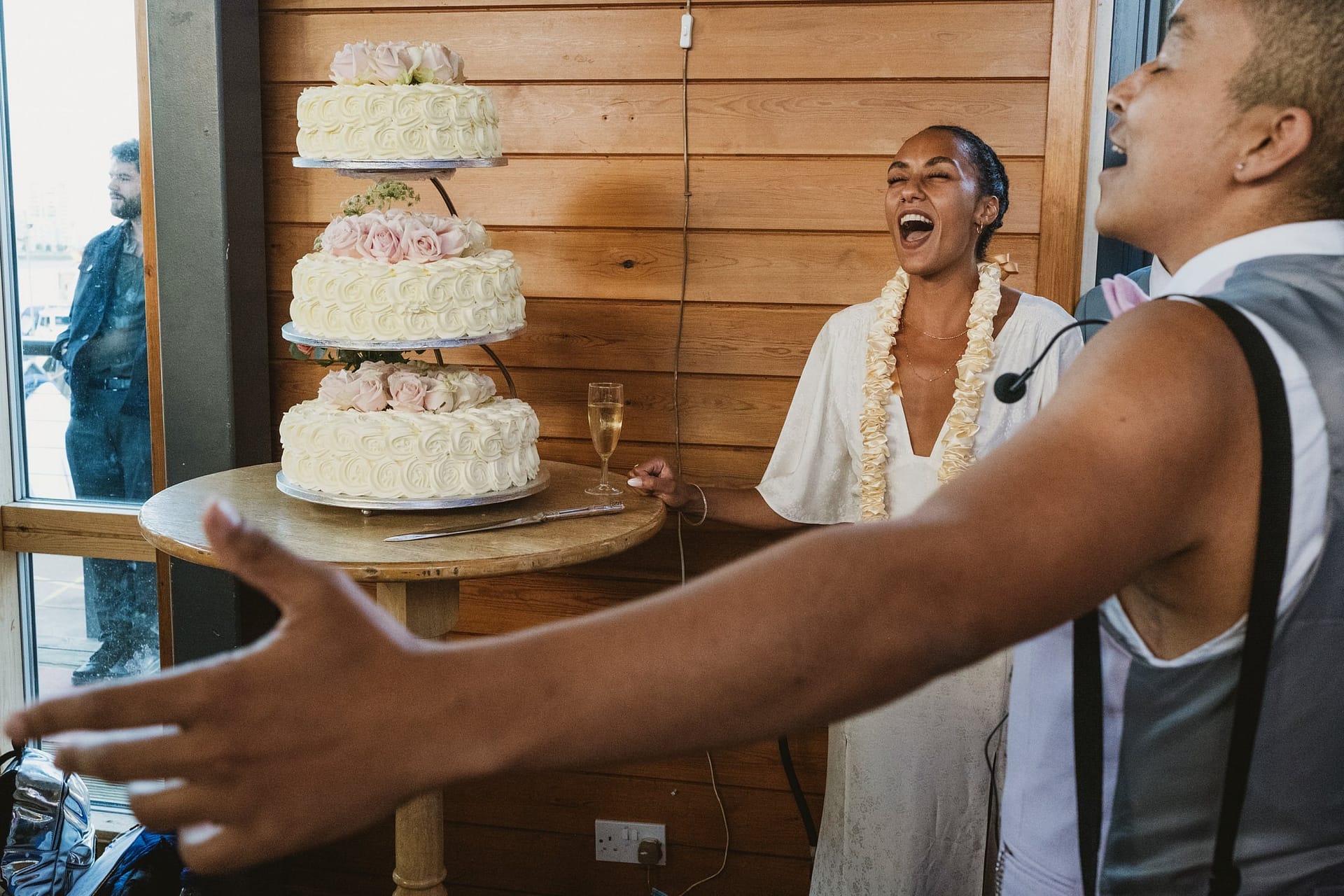 A bride and groom standing next to a wedding cake at their Greenwich Yacht Club wedding.