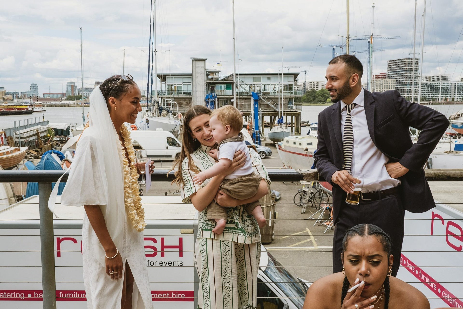A group of people standing on a dock with a baby in their arms, capturing memorable moments at a Greenwich Yacht Club wedding.