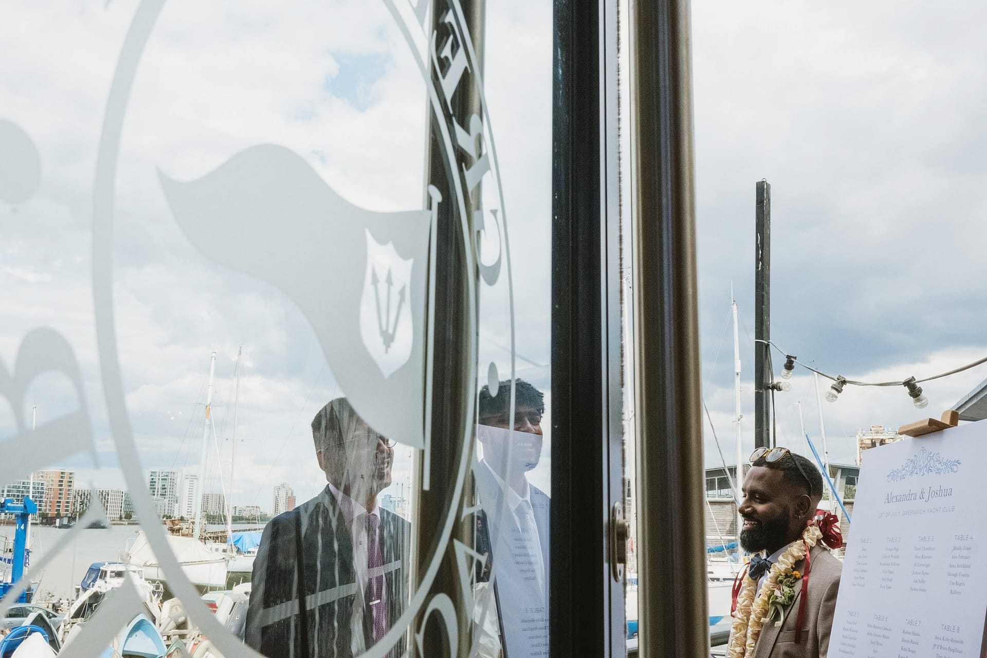 A Greenwich Yacht Club Wedding Photography captures a stunning moment of a bride and groom standing in front of a glass door.