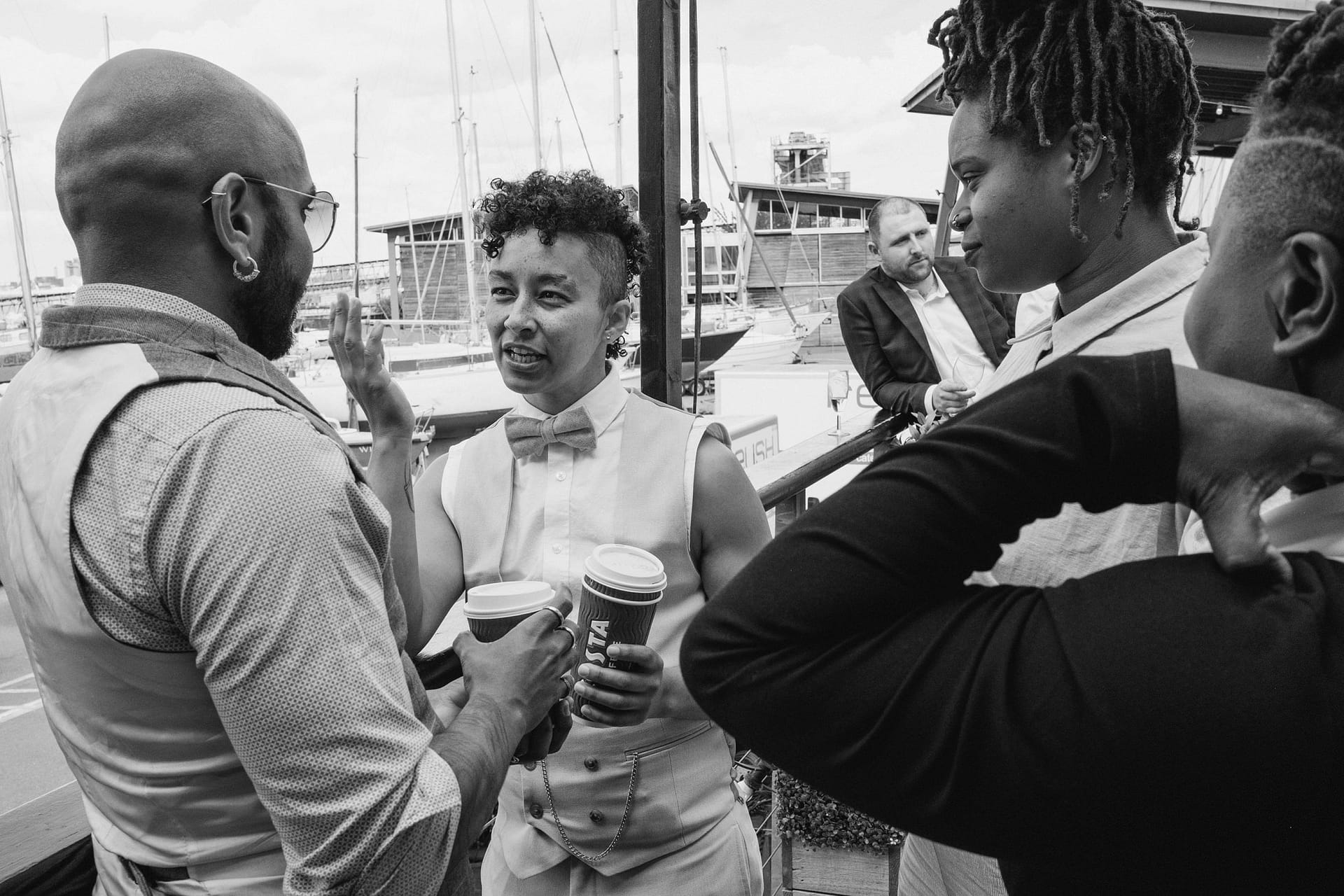 Greenwich Yacht Club Wedding Photography - A black and white photo of a group of people talking at a wedding event.
