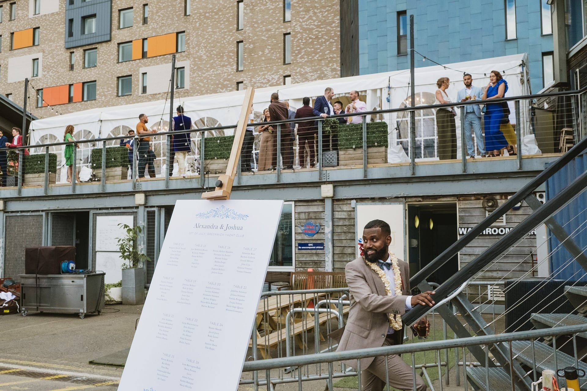 The groom gracefully navigates his way down a metal ladder at the Greenwich Yacht Club, captured beautifully through wedding photography.