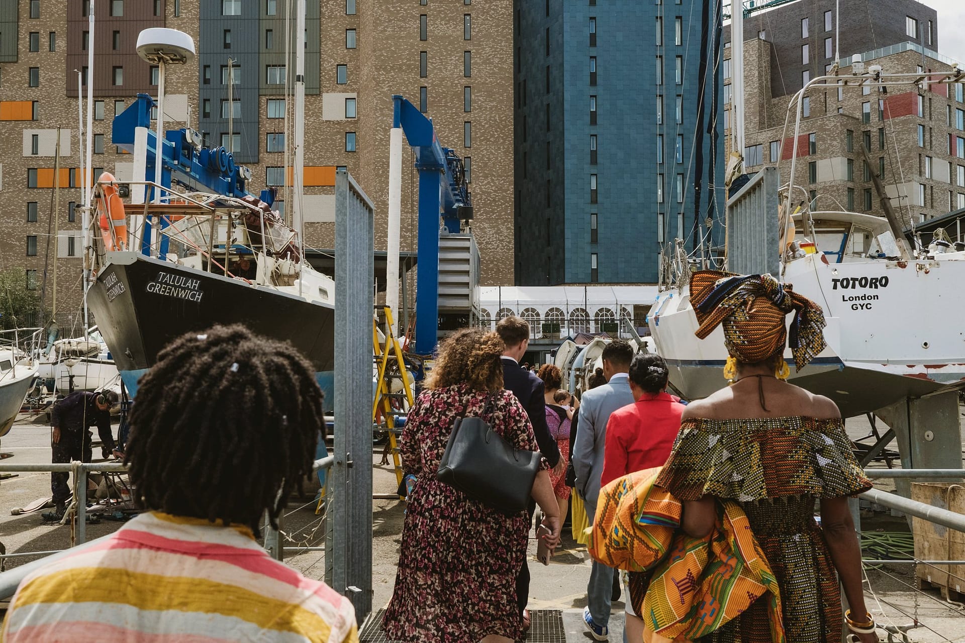 A group of people walking by a dock with boats in the background at Greenwich Yacht Club Wedding Photography.