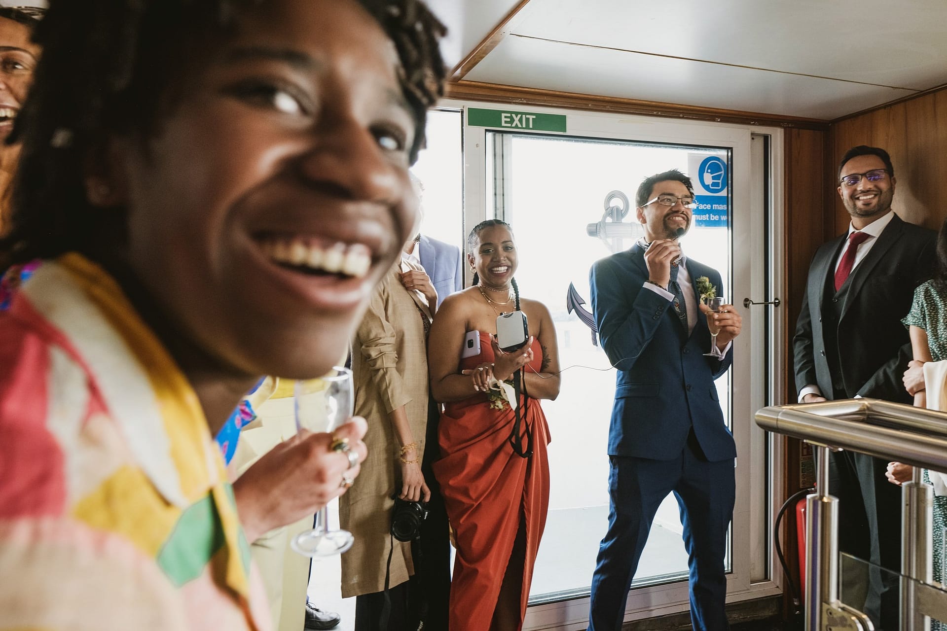 A group of people laughing at a Greenwich Yacht Club wedding party on a boat.