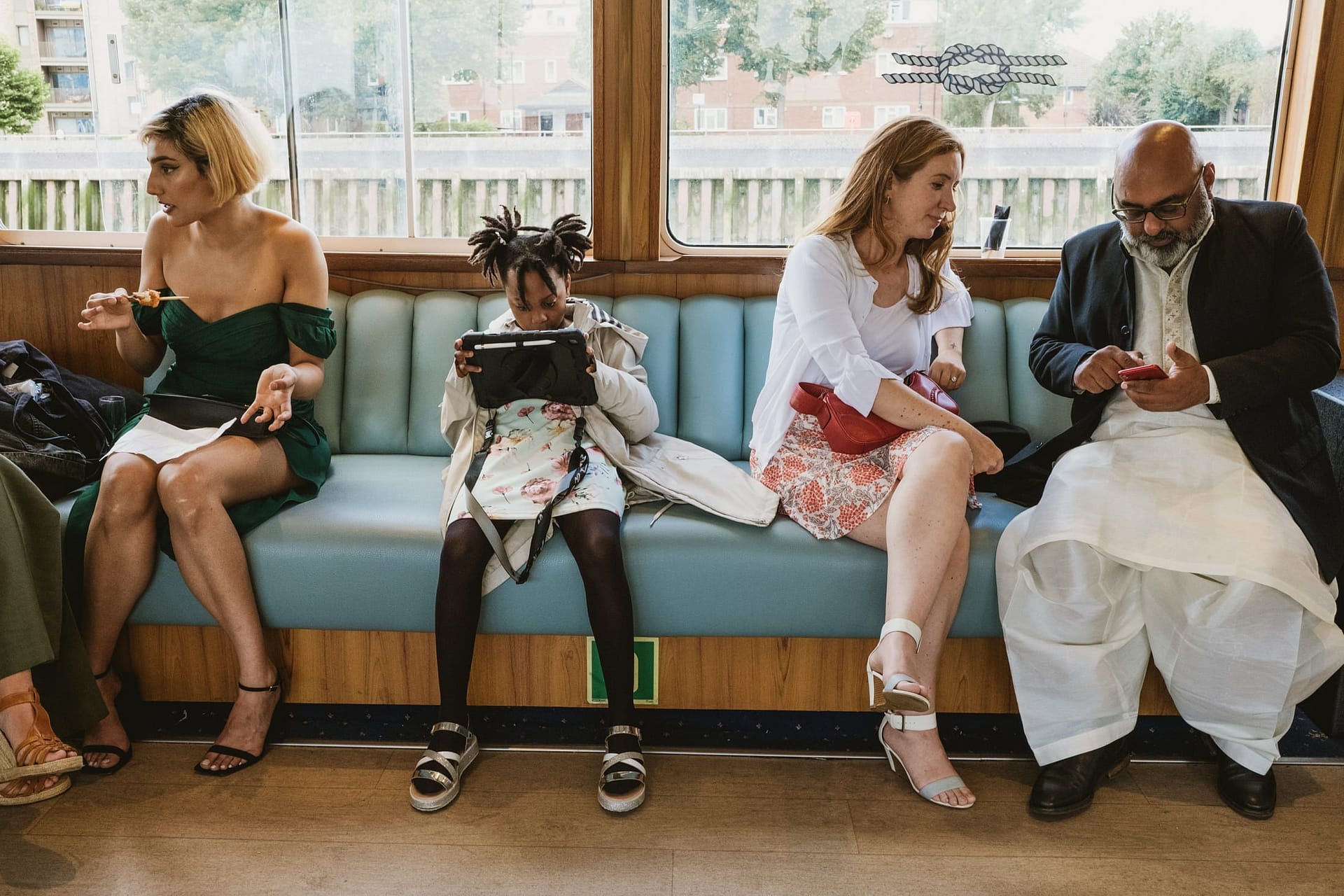 A group of people sitting on a train, absorbed in their phones, completely oblivious to their surroundings.