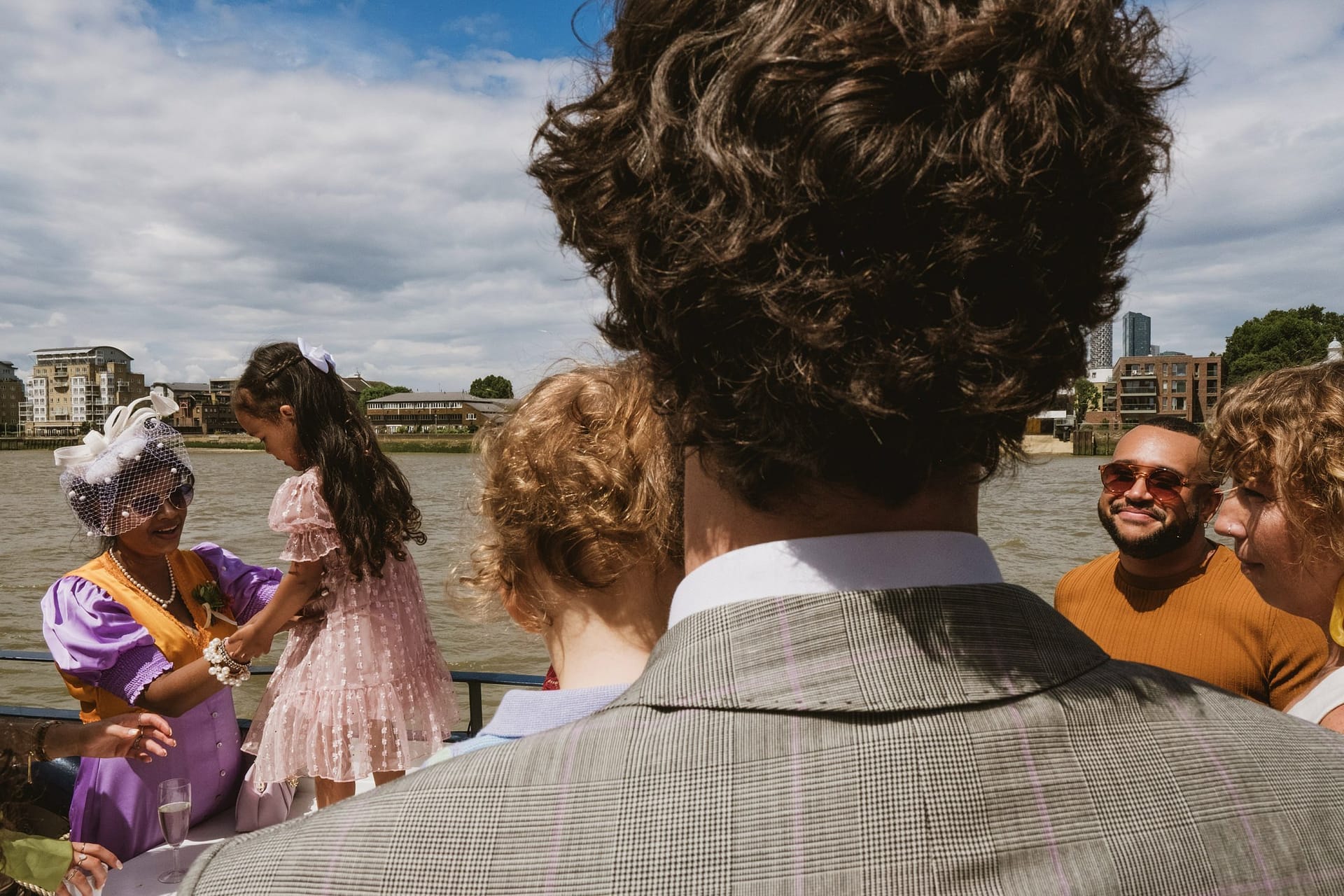 A group of people on a boat at the Greenwich Yacht Club, enjoying the river scenery while capturing memorable moments through wedding photography.