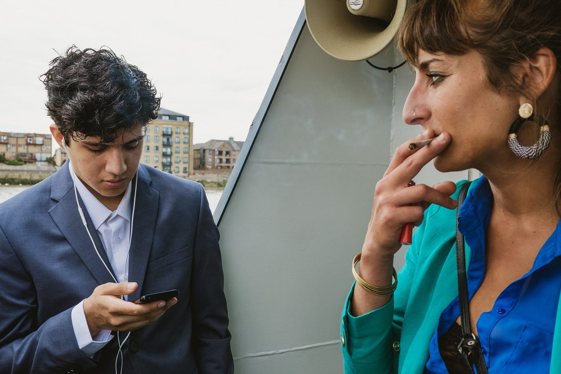 A man and woman are looking at a mobile phone on a Greenwich Yacht Club boat during their wedding photography session.