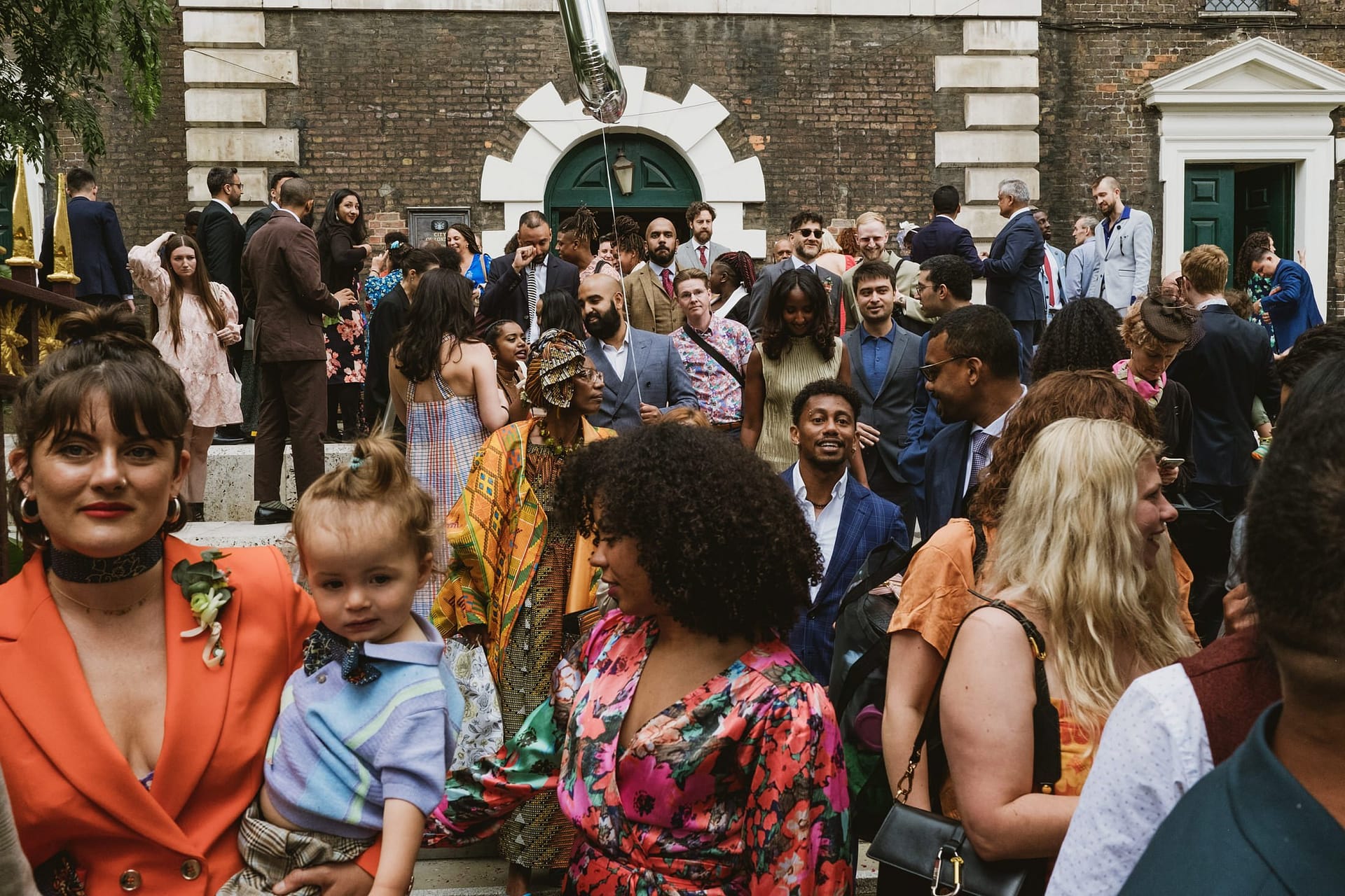 A crowd of people gathered in front of the London church for a photography session capturing the beautiful moments of a wedding.