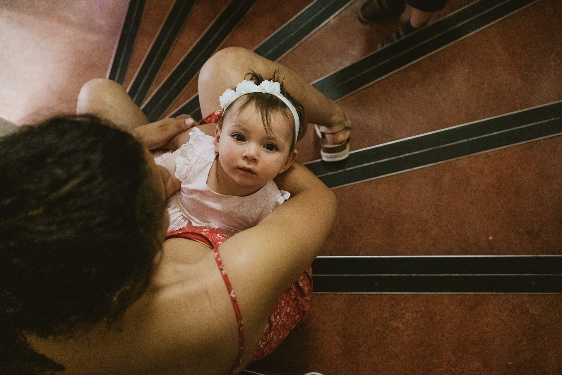 A woman is holding a baby on the stairs, capturing a beautiful moment during a Greenwich Yacht Club Wedding Photography.