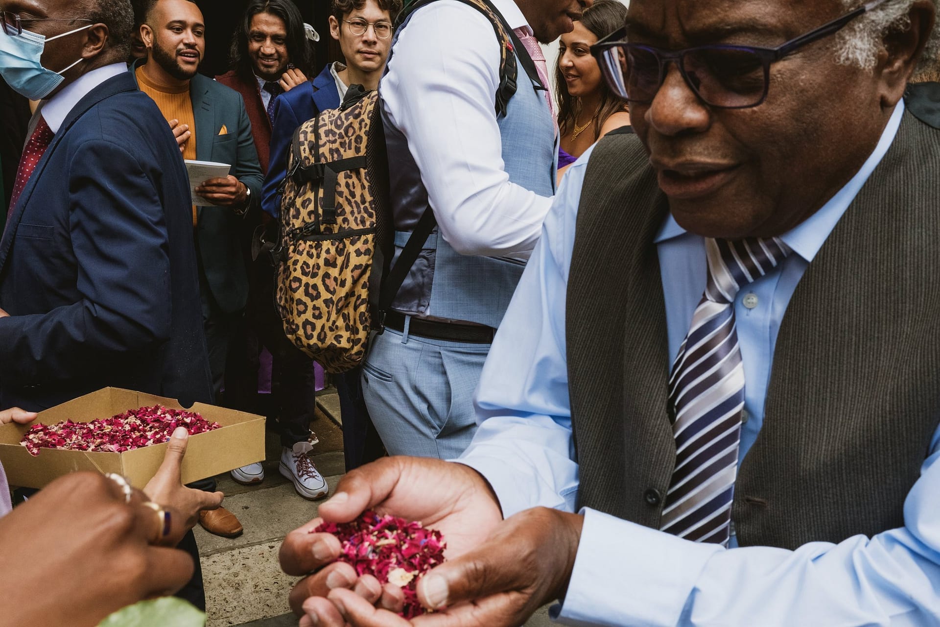 A man in a suit is handing out roses to a group of people at a Greenwich Yacht Club wedding.