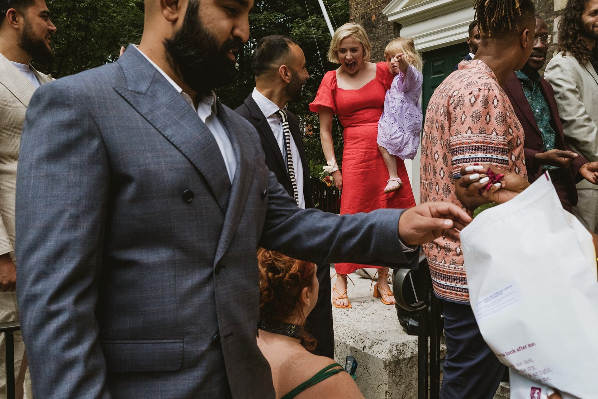 A man in a suit is handing out a paper to a group of people at the Greenwich Yacht Club's wedding, captured beautifully through photography.