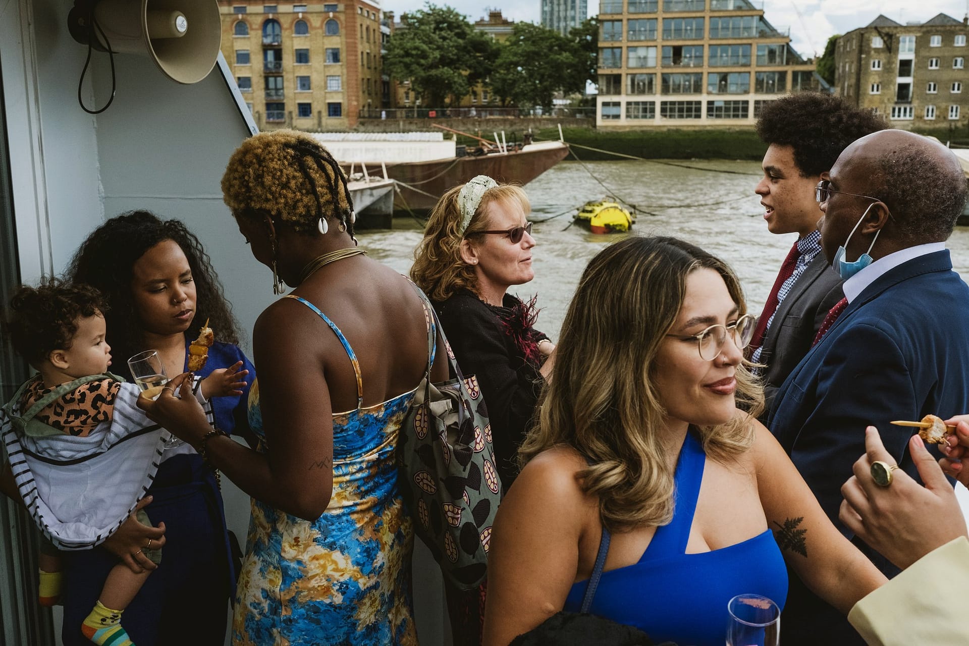 A group of people standing on a boat near the Greenwich Yacht Club in London.