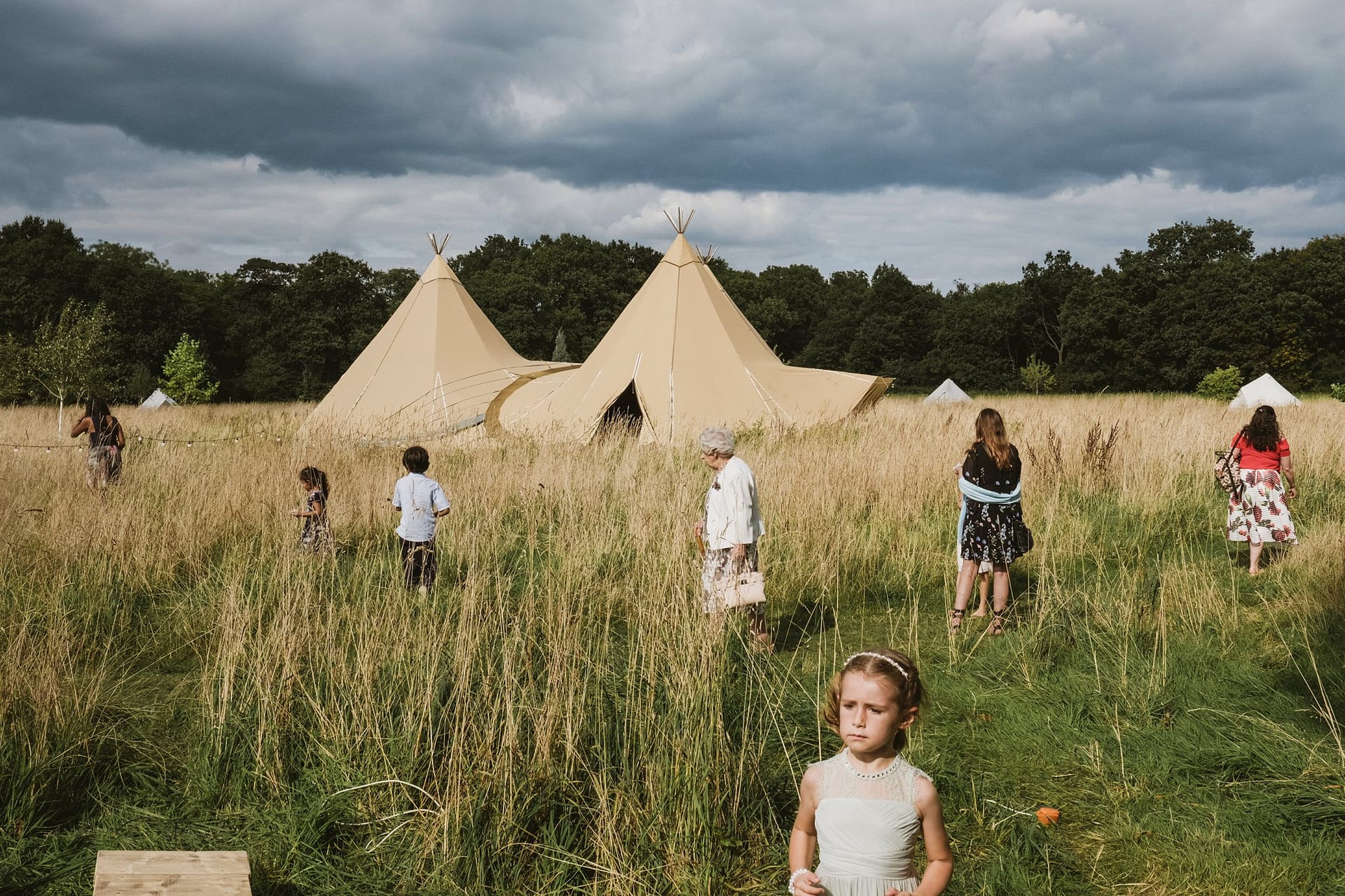 wedding guests spaced out in a field next to the teepees at Home Farm Glamping