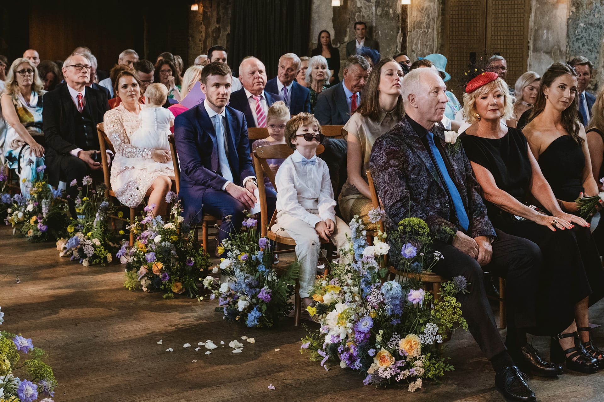 Guests seated at a wedding ceremony with flowers.