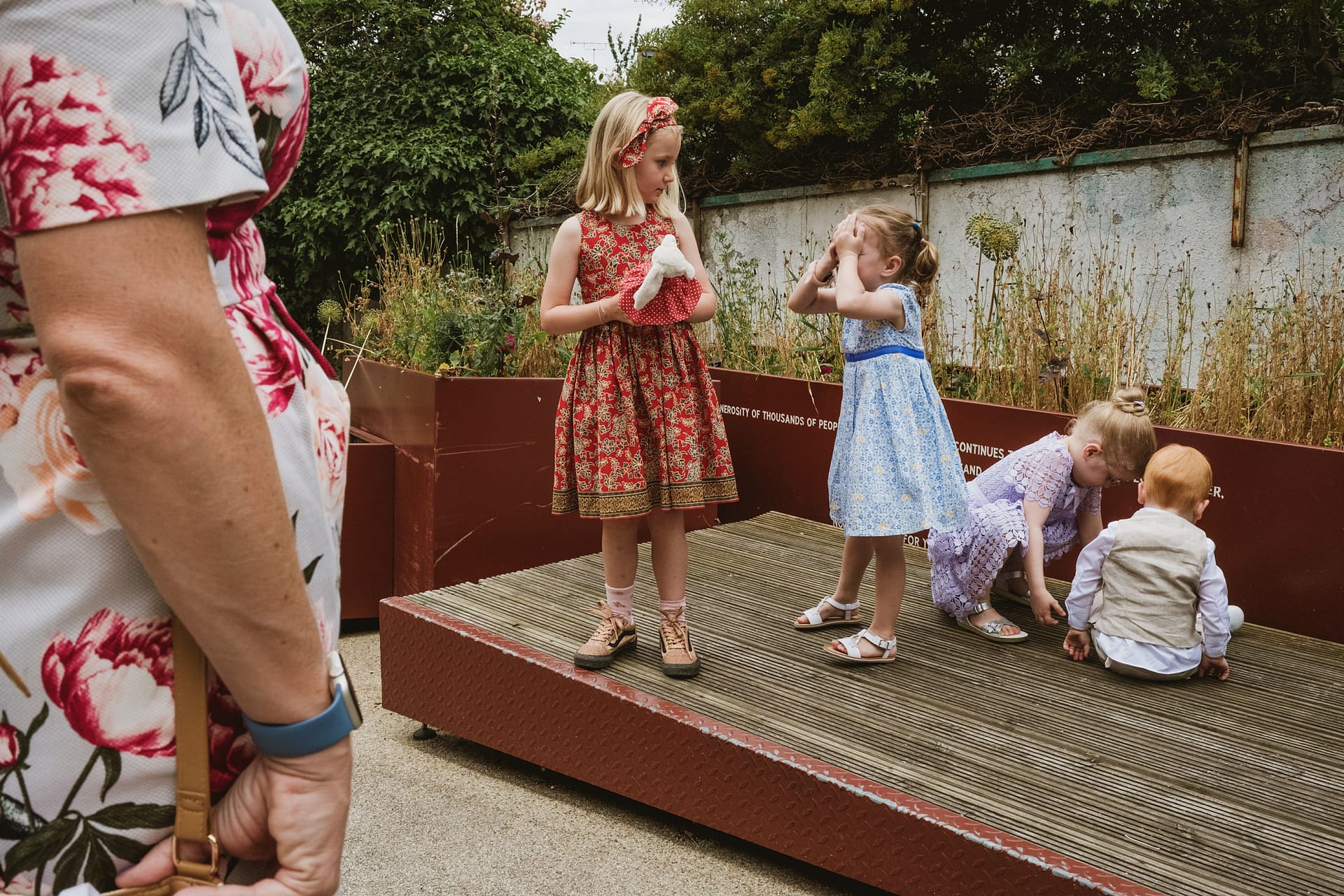 Children playing on a wooden platform outdoors.