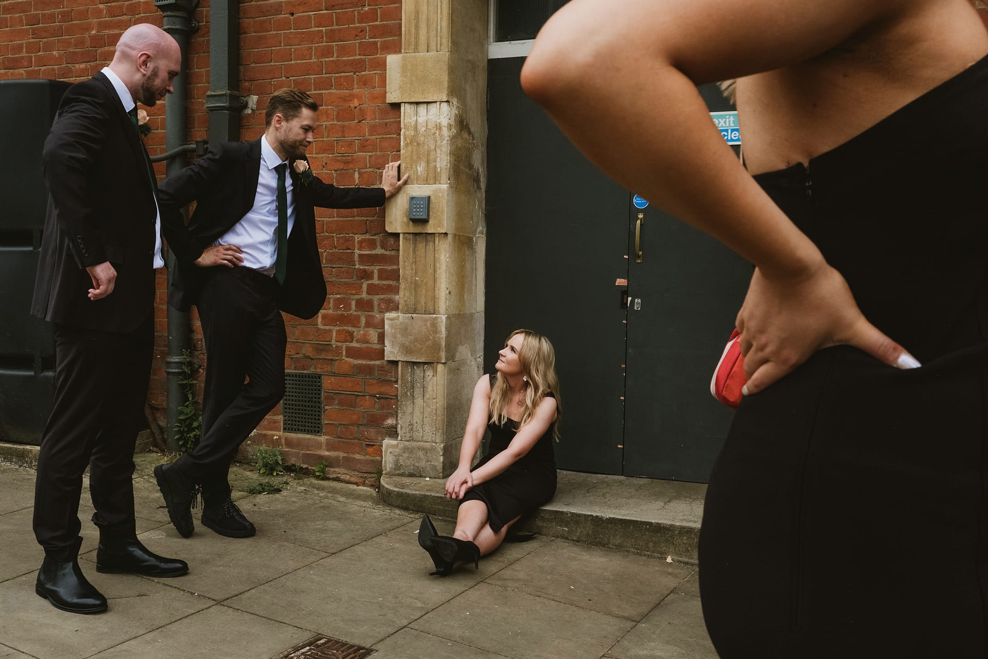 Group in formal wear outside brick building.