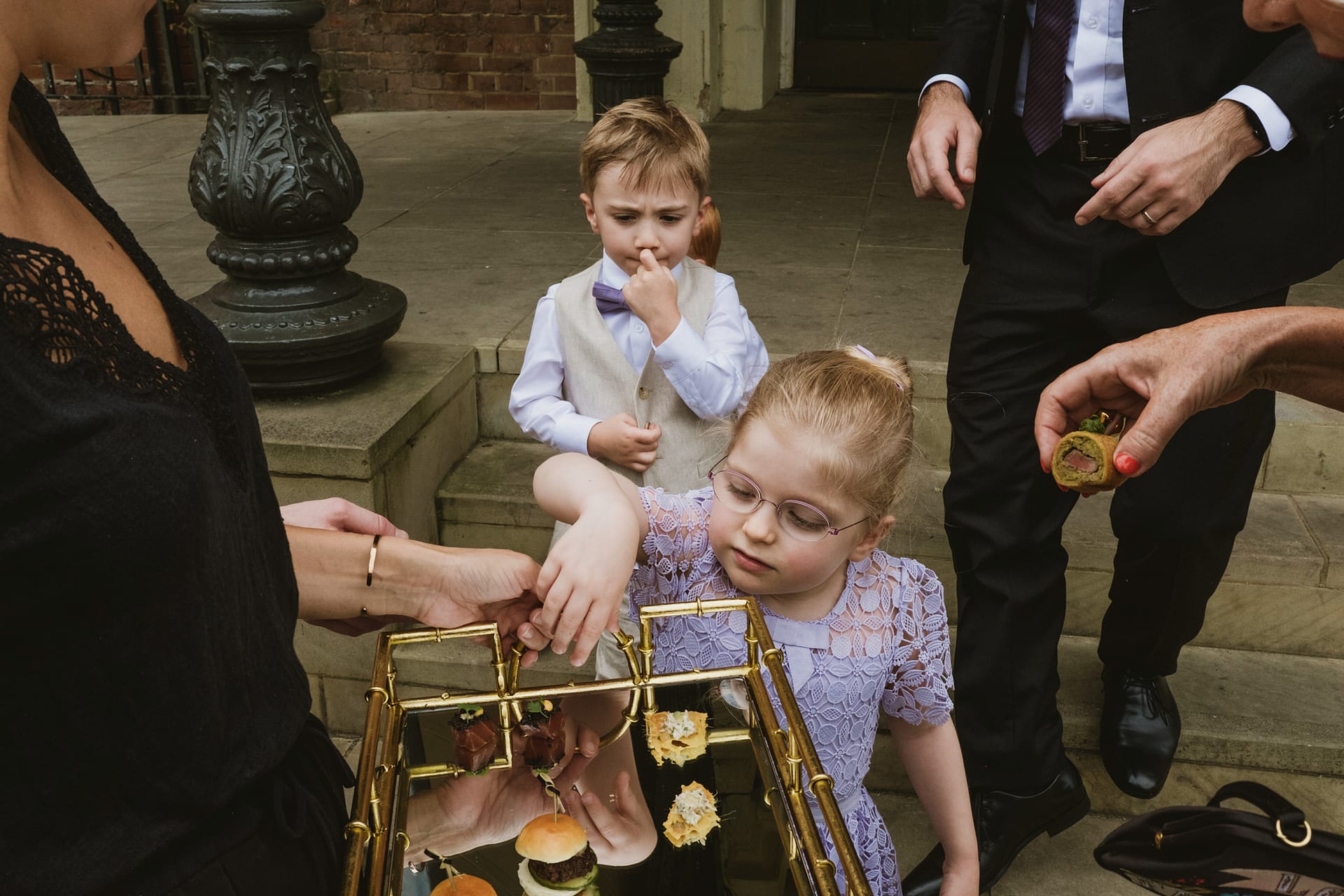 Children selecting snacks from a tray at event.