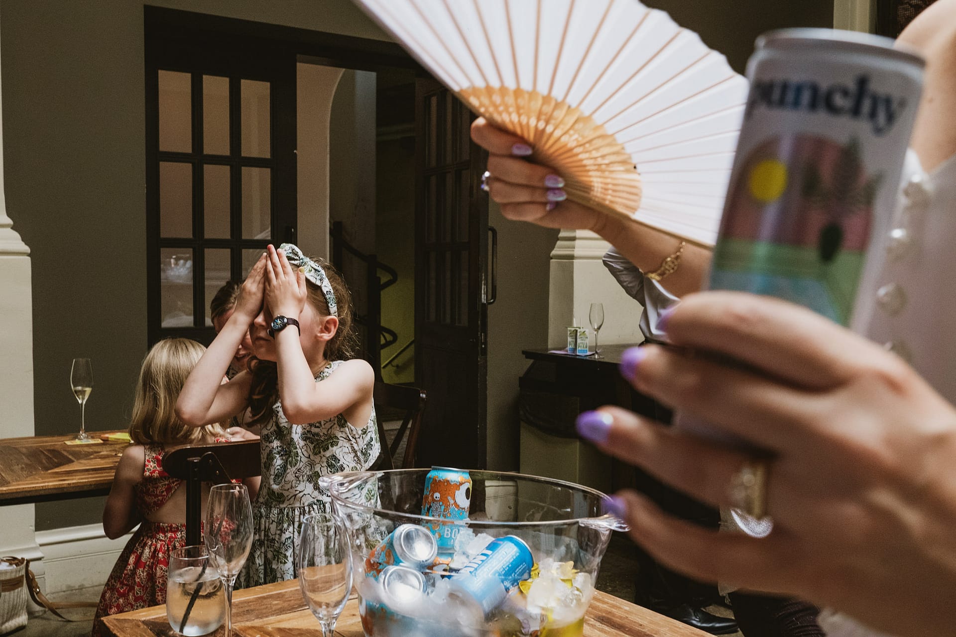 Children playing with drinks and an open fan.