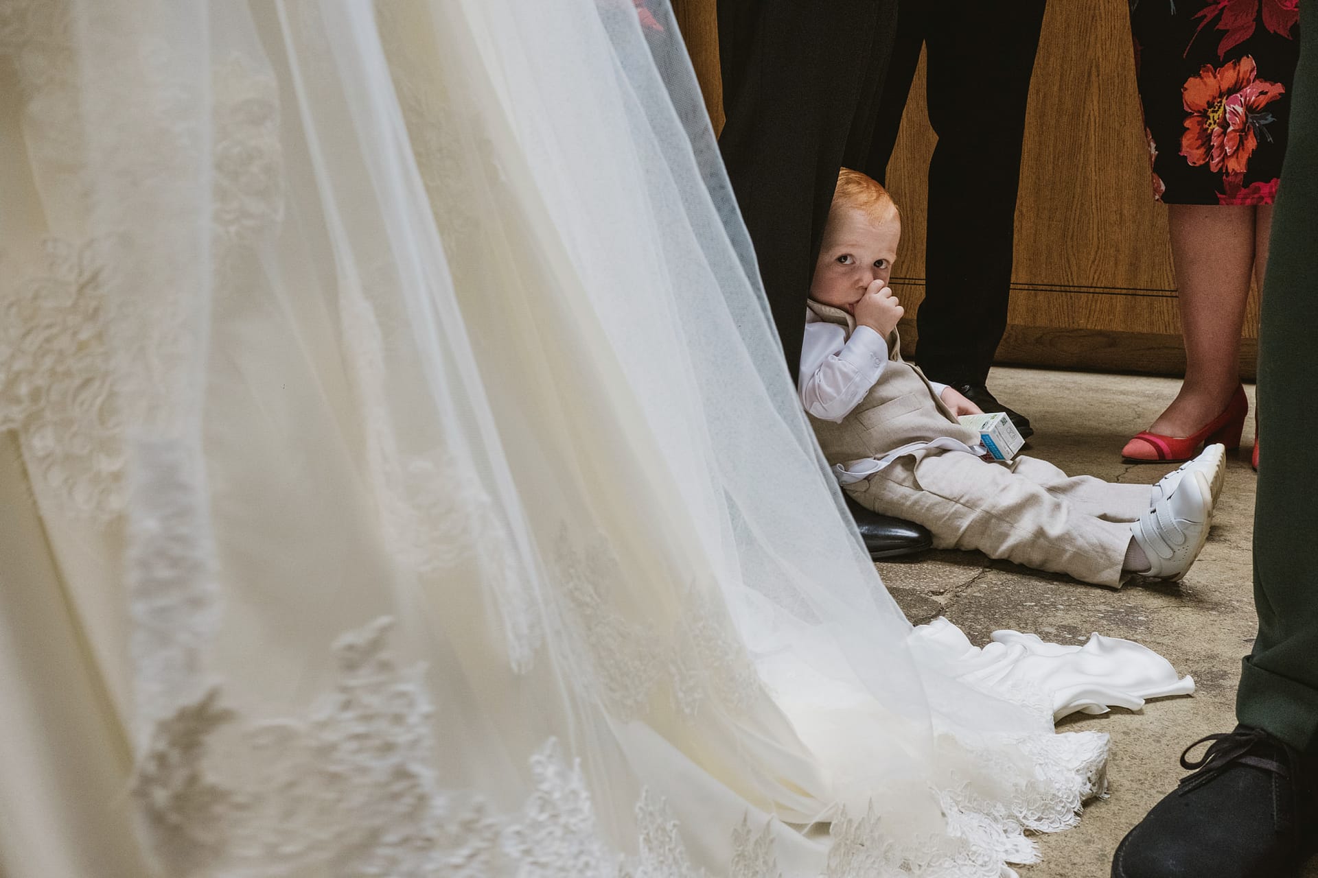 Child hiding under wedding dress during ceremony.