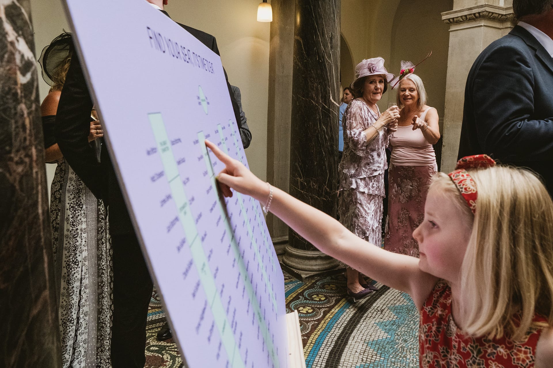 Child pointing at seating chart at wedding.