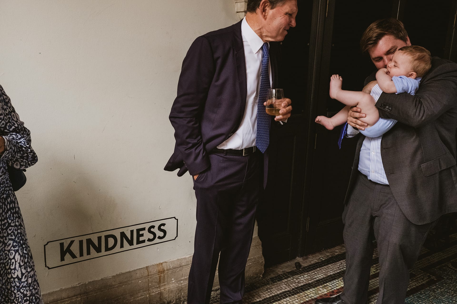 Two men with baby near kindness sign