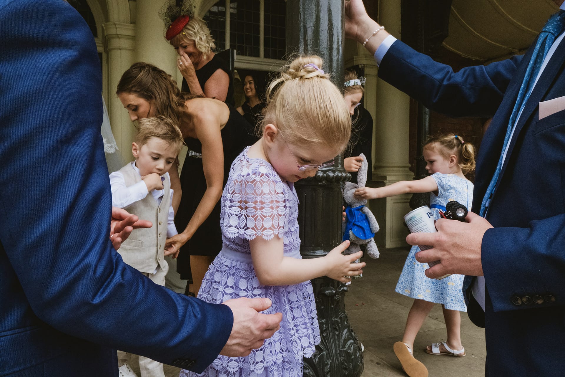 Children playing at a formal event with adults nearby.