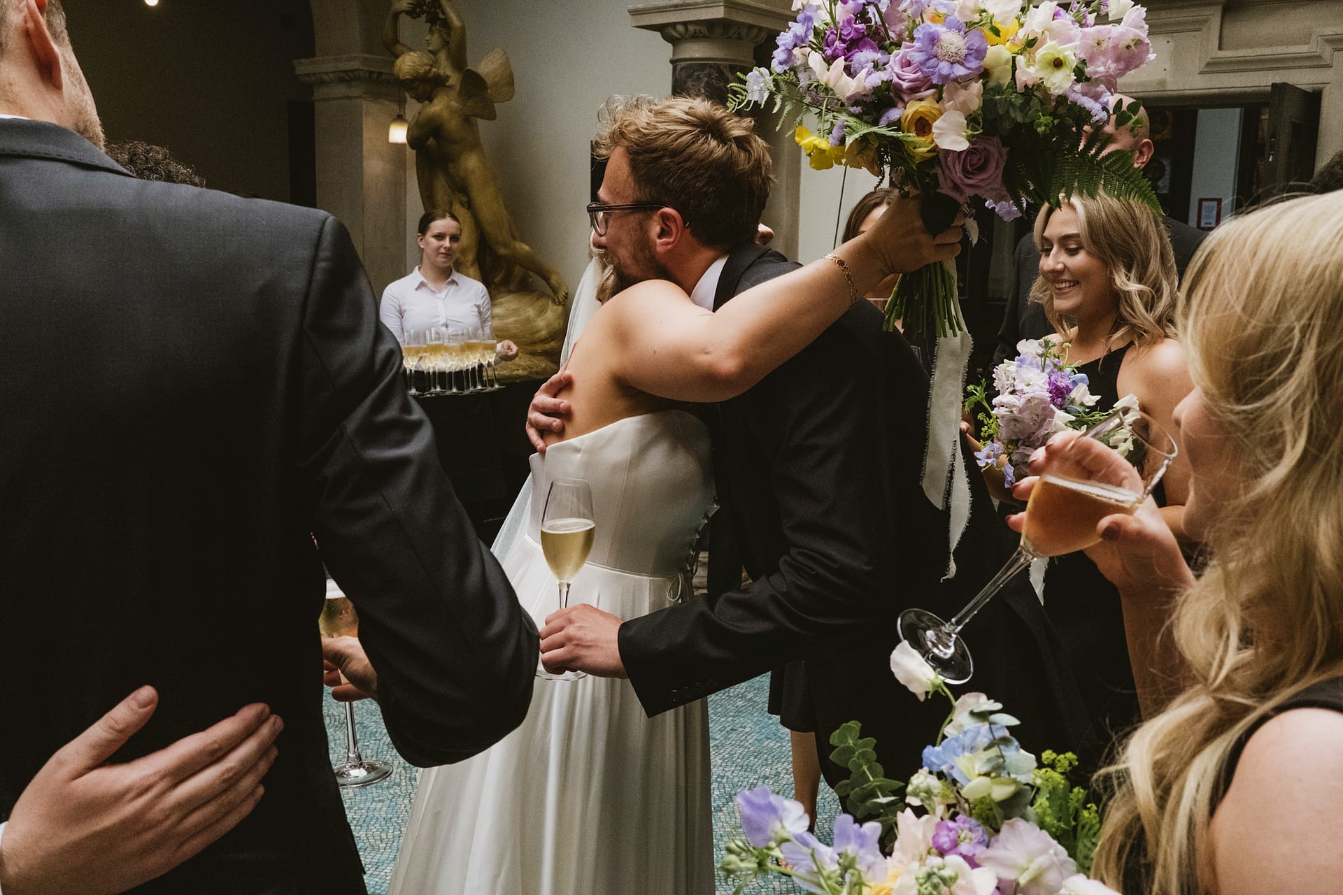 Wedding guests hugging with flowers and drinks.