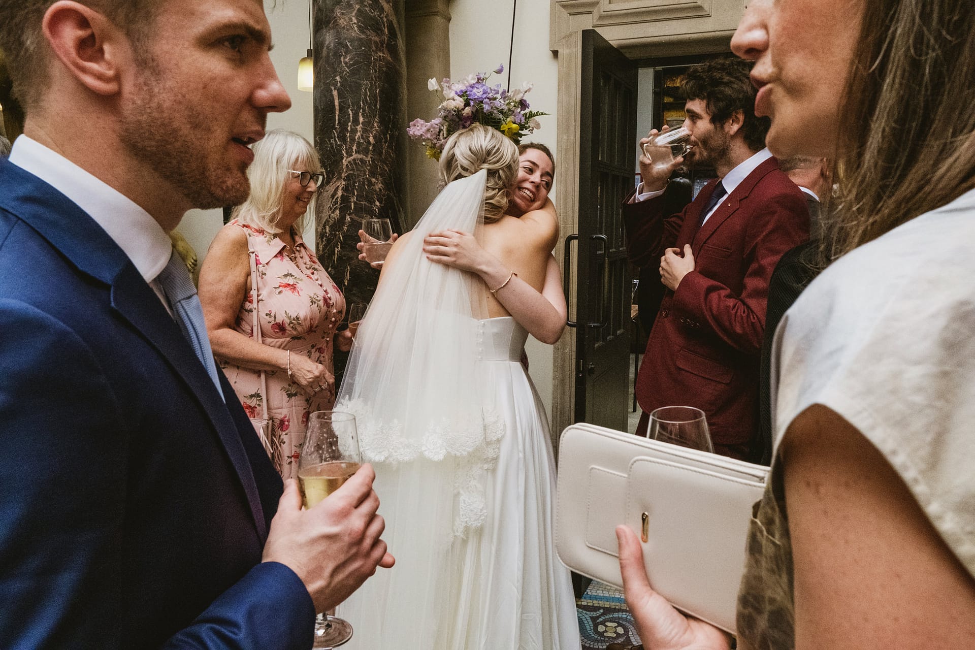 Wedding guests celebrate with bride and friends hugging.