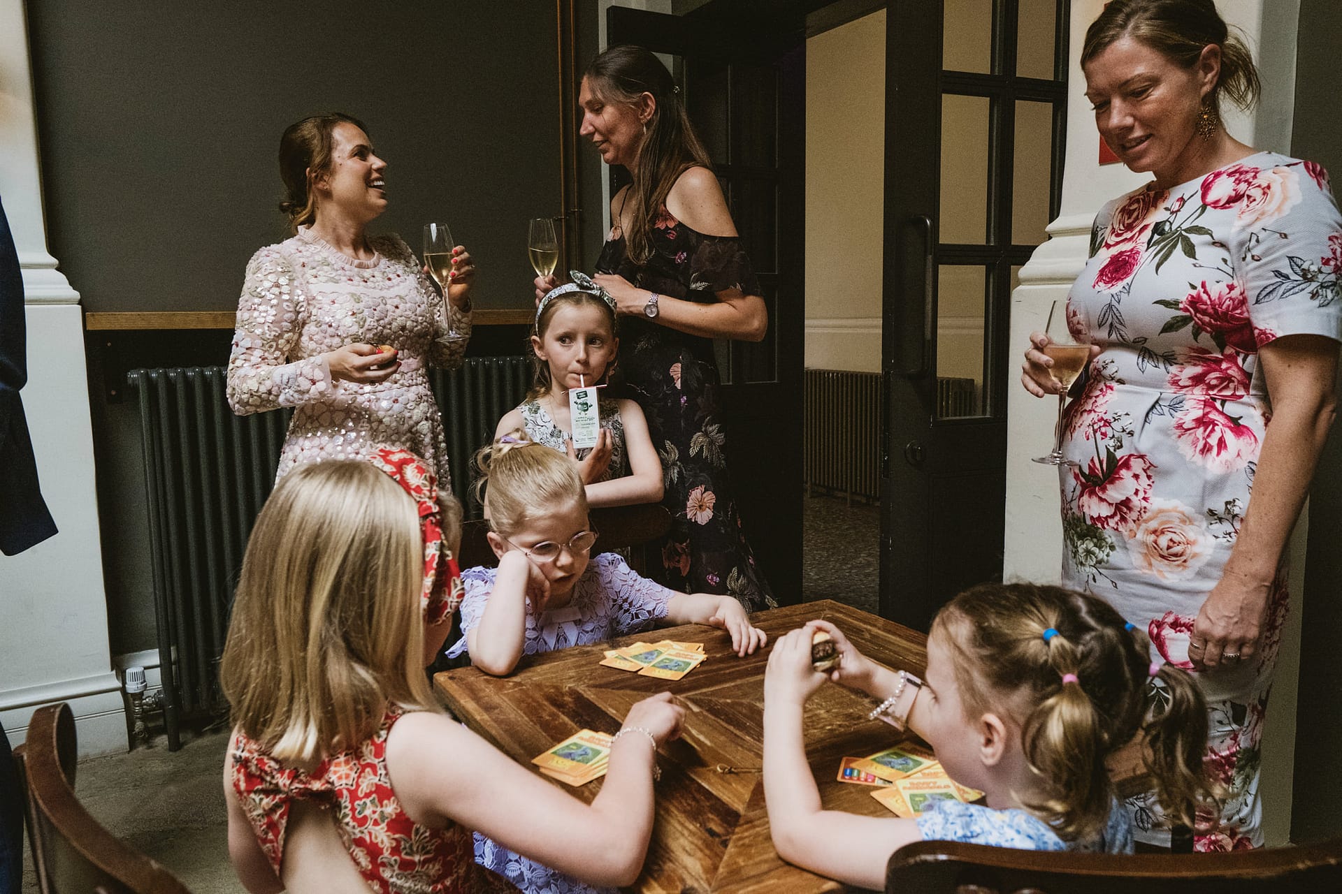 Women and children at a social gathering, playing cards.