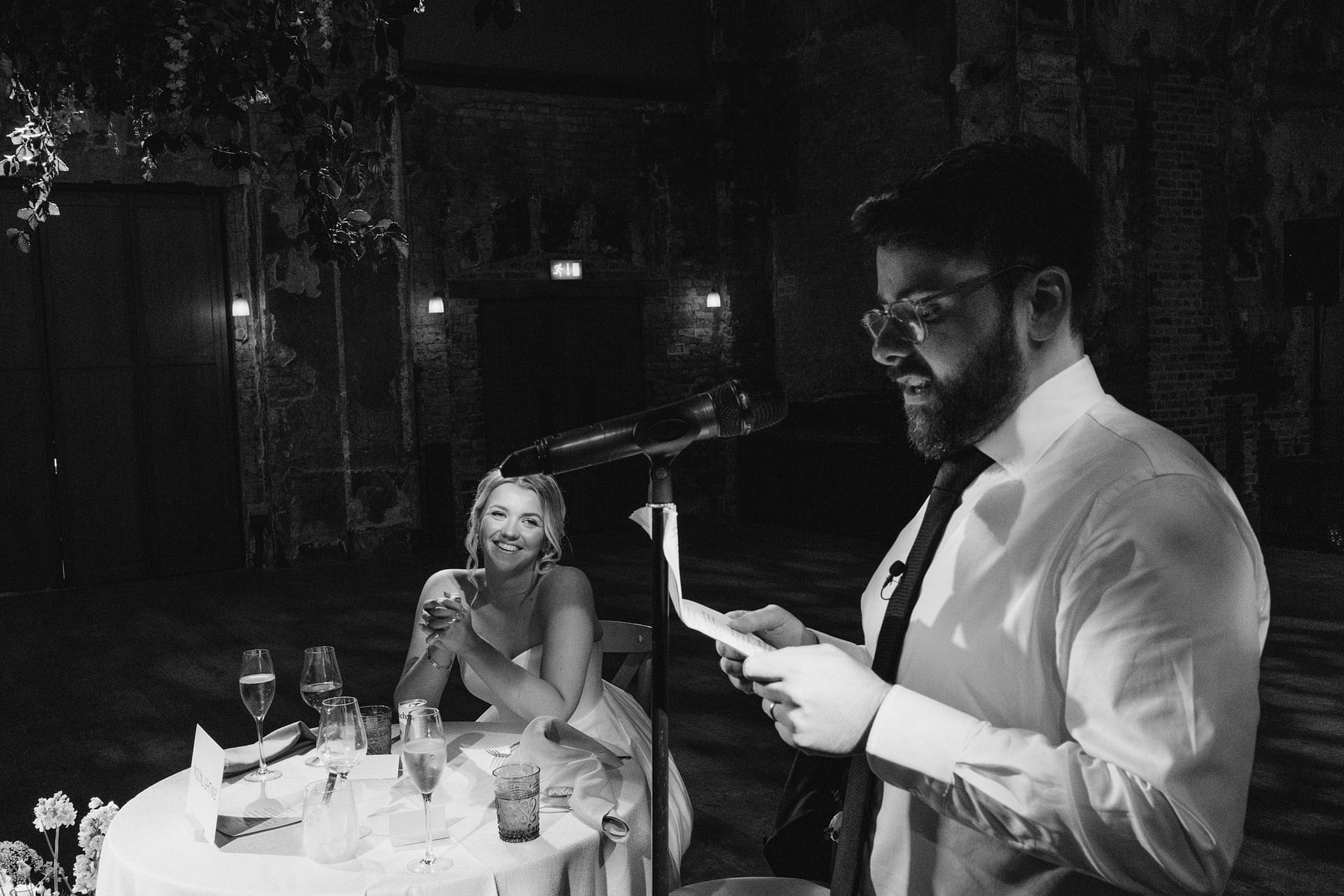 Person giving wedding speech, woman smiling at table.