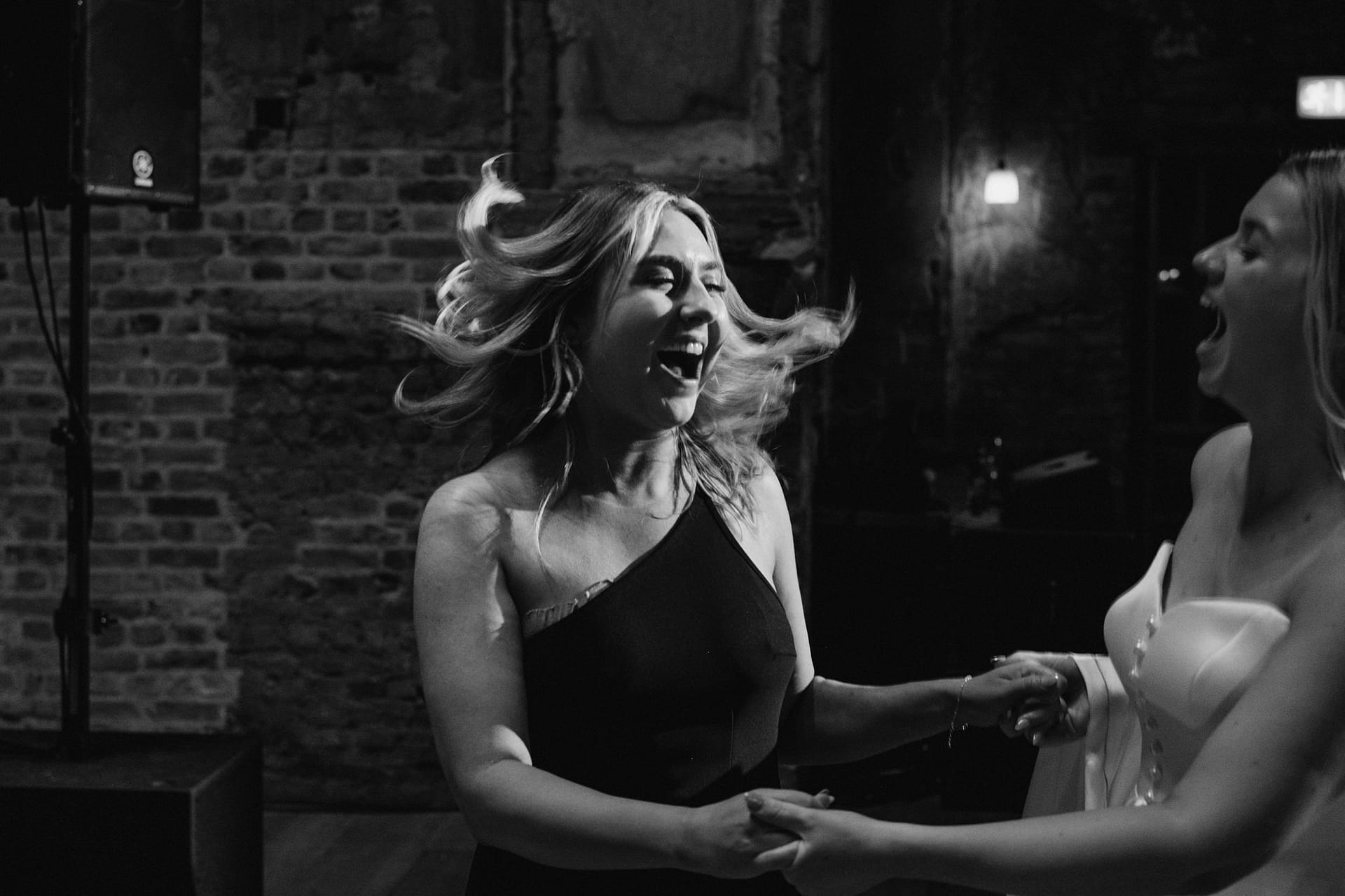 Two women laughing and dancing indoors.