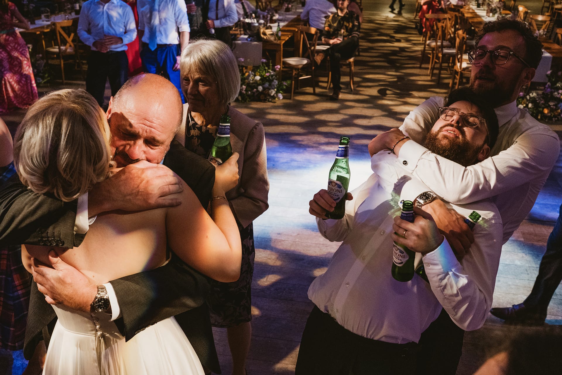 People hugging and laughing at a wedding reception.