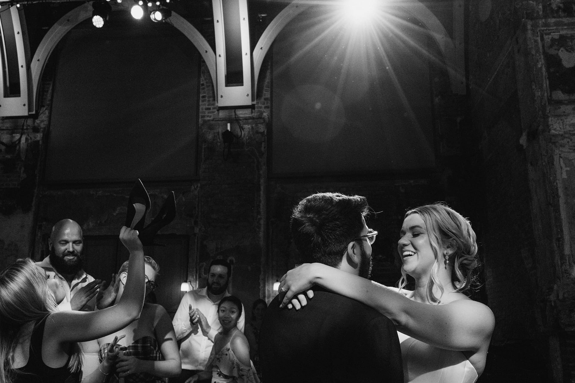 Couple dancing at wedding reception, happy guests around.