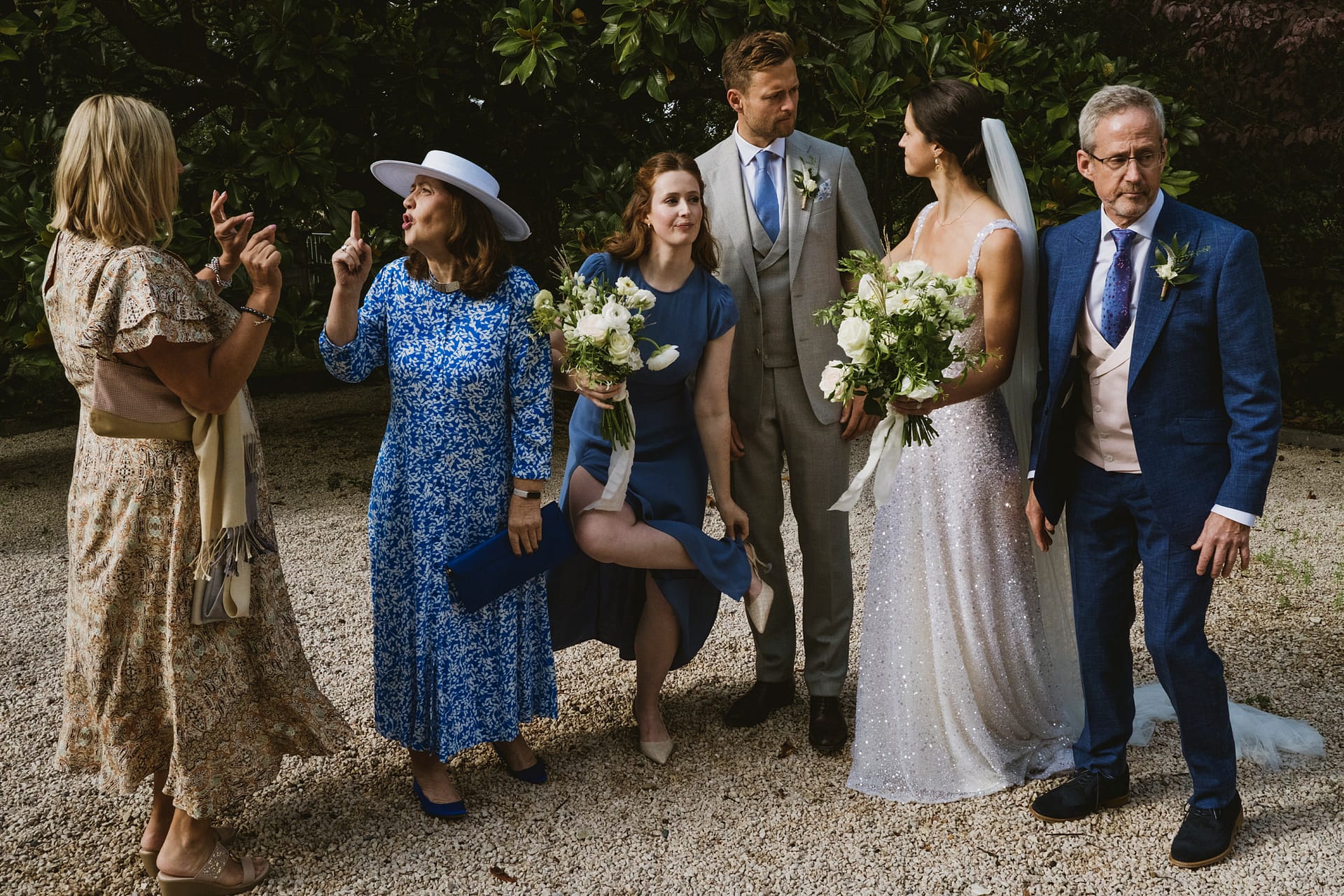 Outdoor wedding group with bouquets and formal attire.