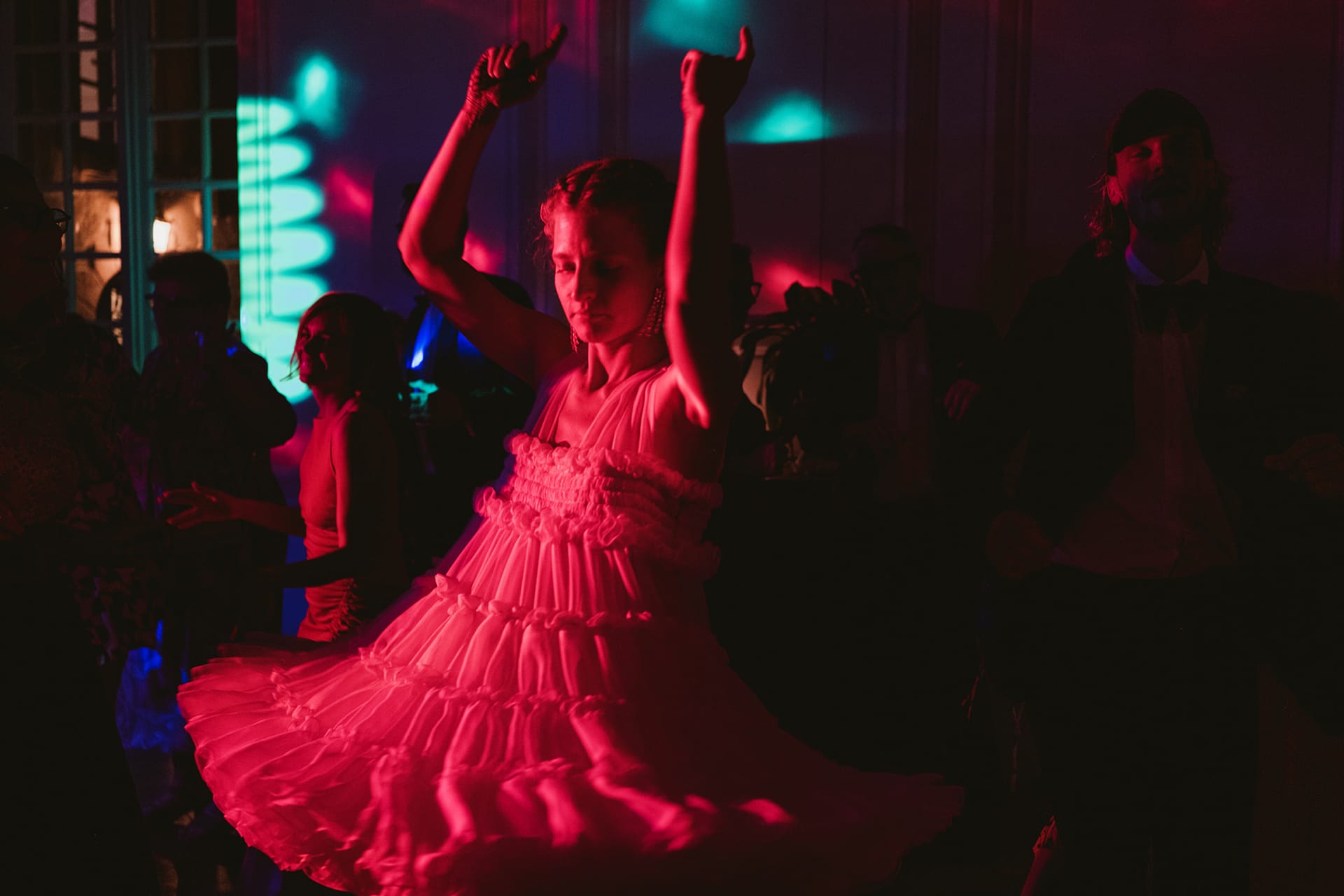 The bride bathed in red light on the dance floor at the Chateau du Fey wedding reception