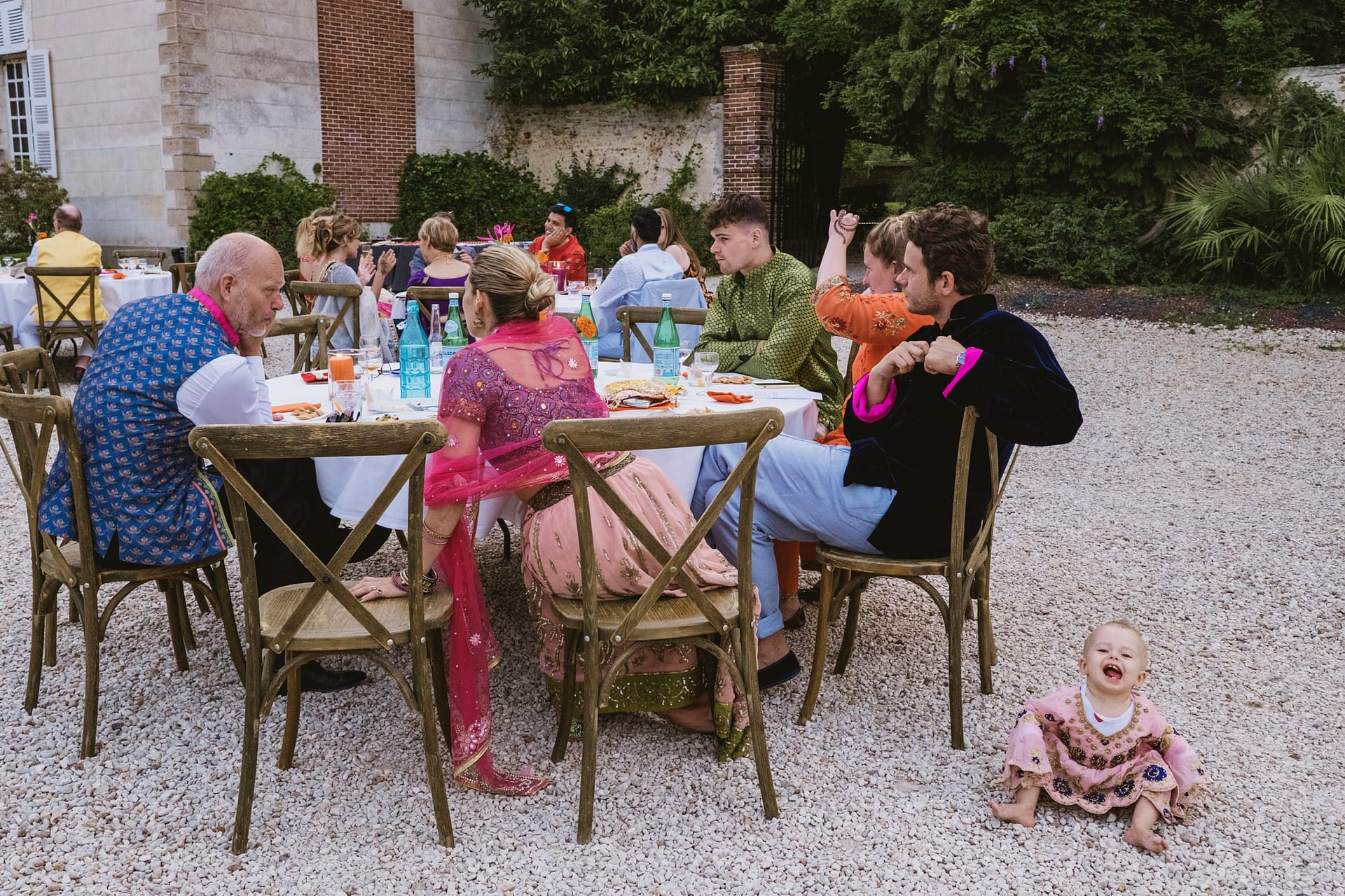 The baby laughs on the floor whilst the adults sit at the table at the Chateau du Fey wedding venue in France
