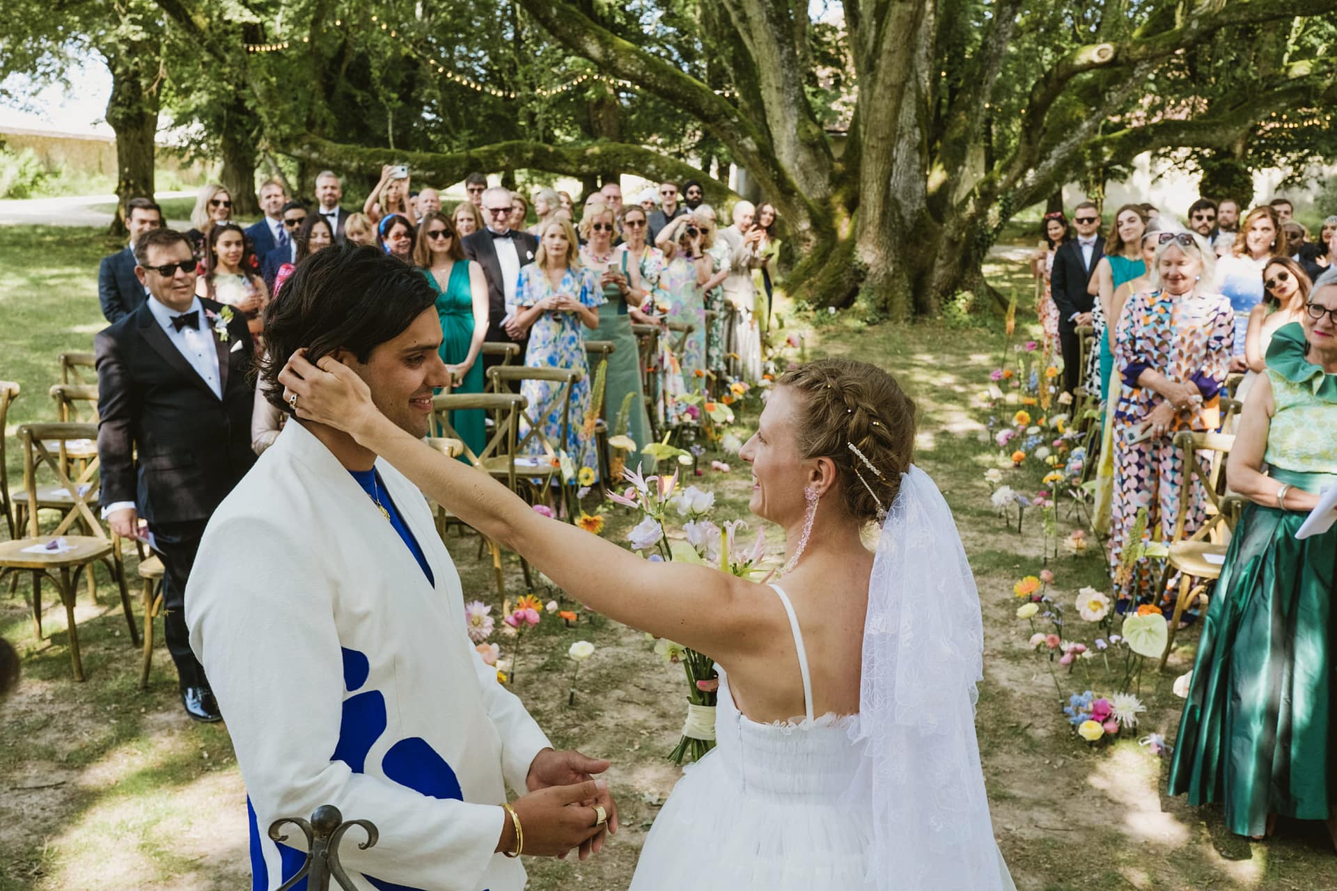 bride caresses her groom's face during the Chateau du Fey wedding ceremony