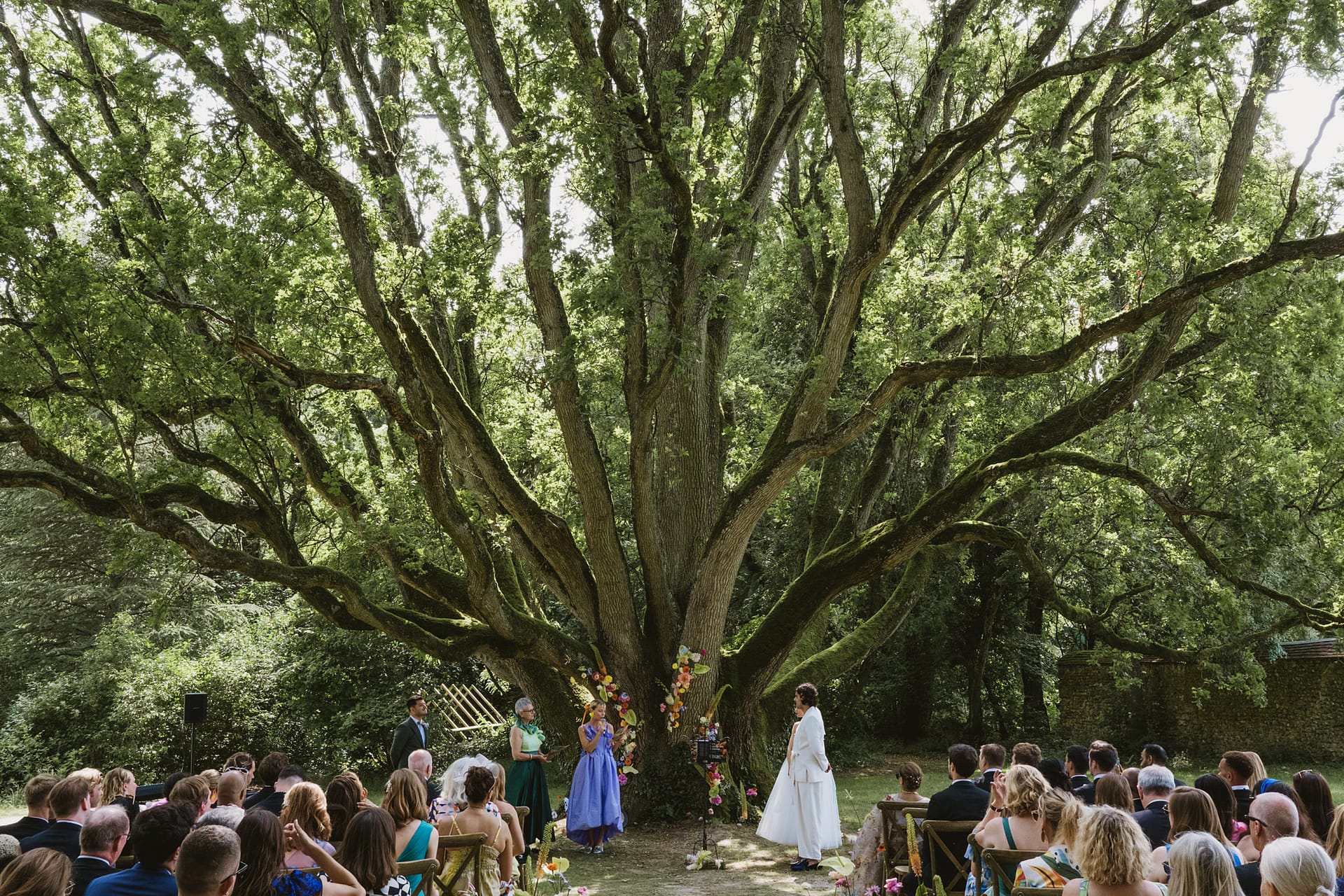 Wedding ceremony reading. Beautiful tree and flower backdrop at Chateau du Fey in France