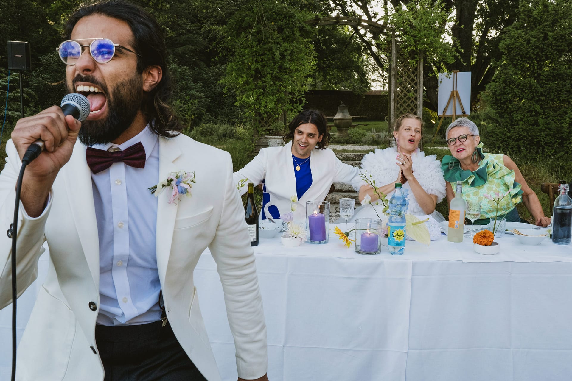The best man singing his speech in the Chateau du Fey in France. Groom, bride and bride's mother look on.