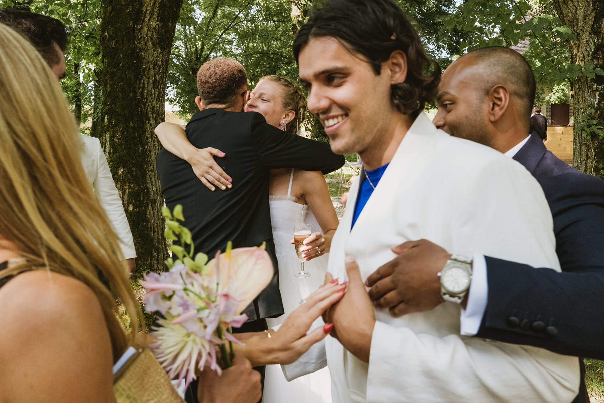 bride hugs wedding guests whilst groom gets a hug from behind at Chateau du Fey in France