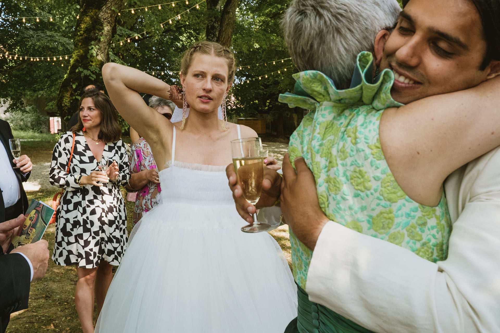 bride emotionally looks on whilst the groom hugs the mother of the bride at Chateau du Fey in France