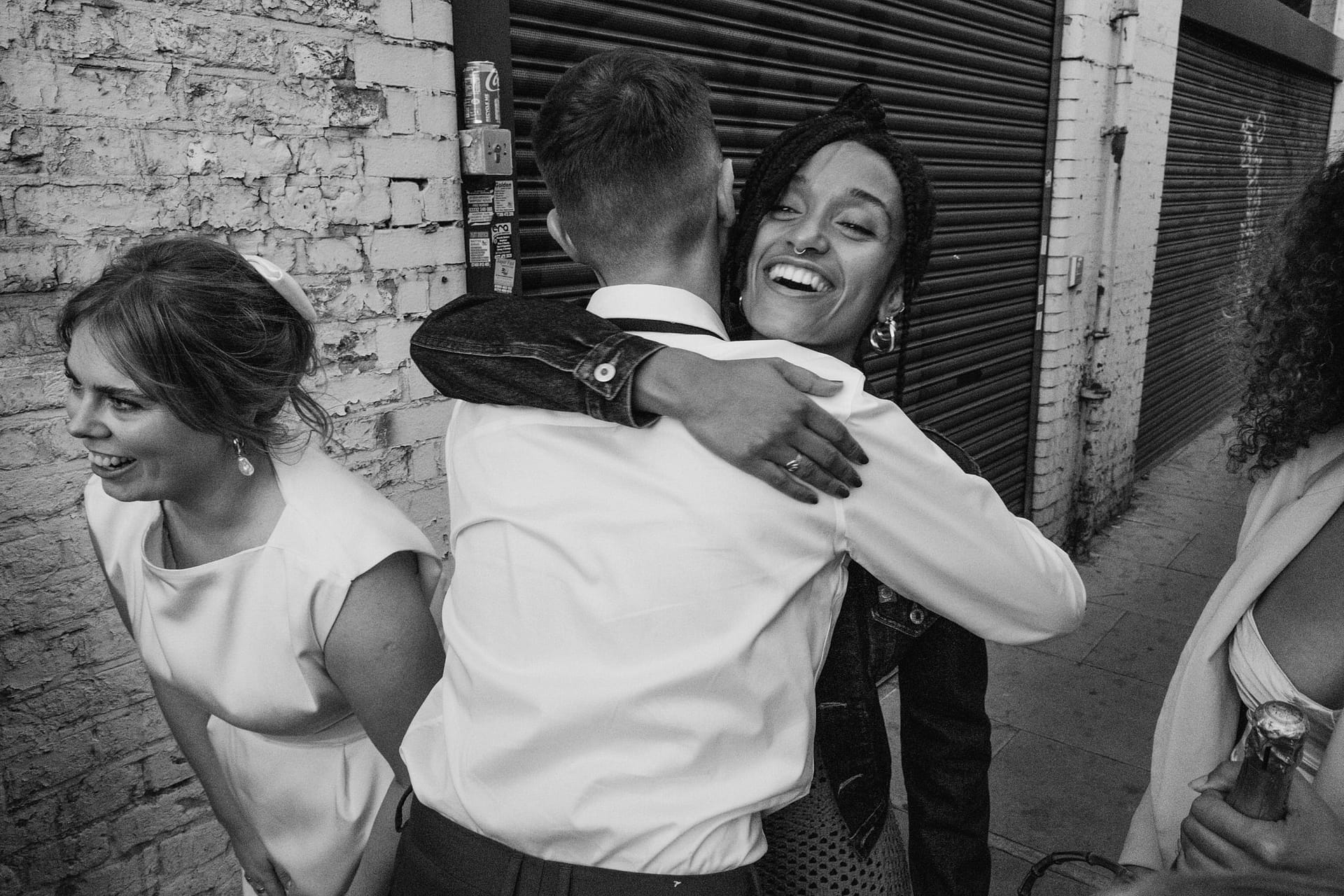 Three people hugging and laughing outside.