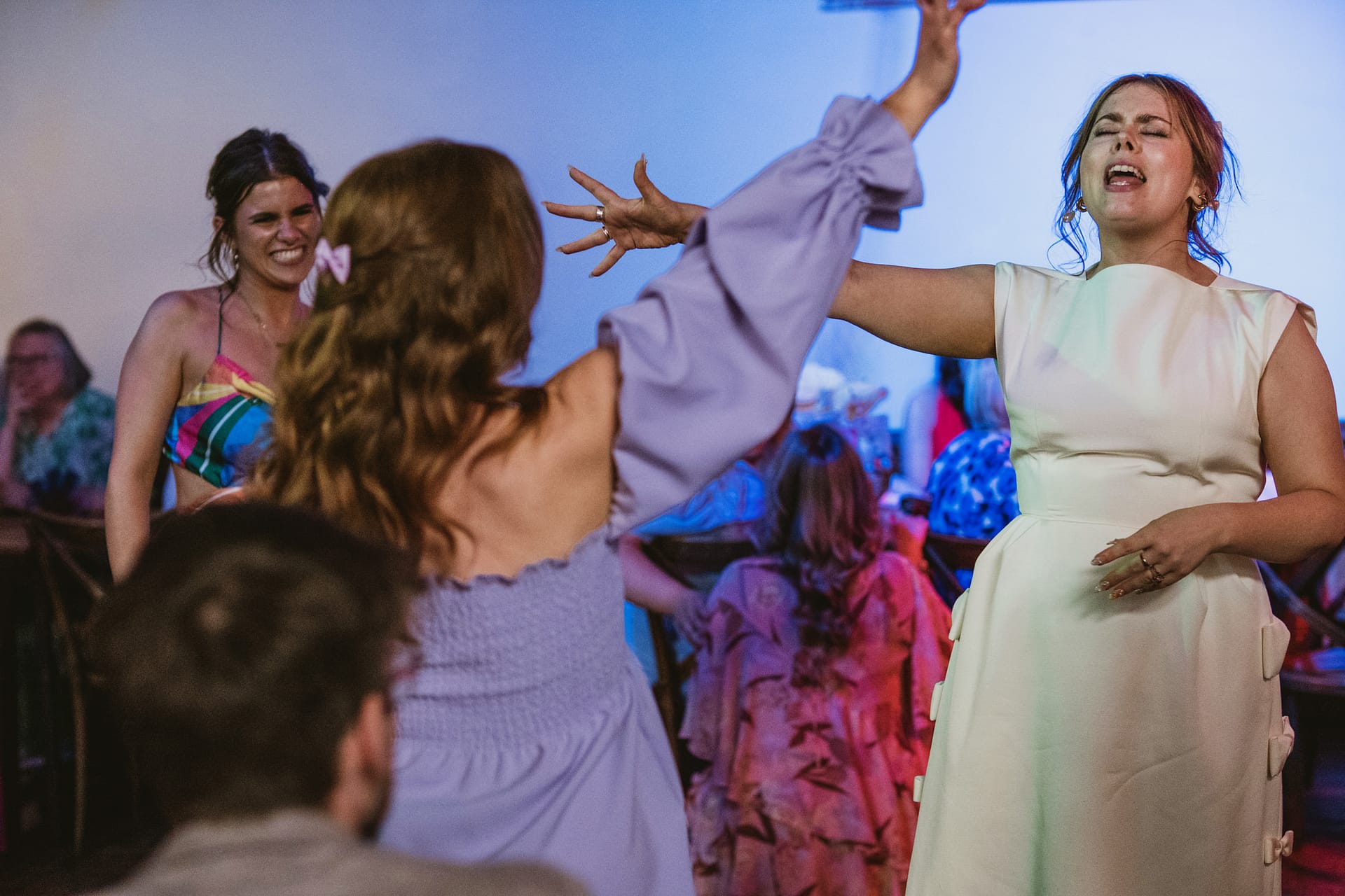 Women dancing and singing at a lively party.