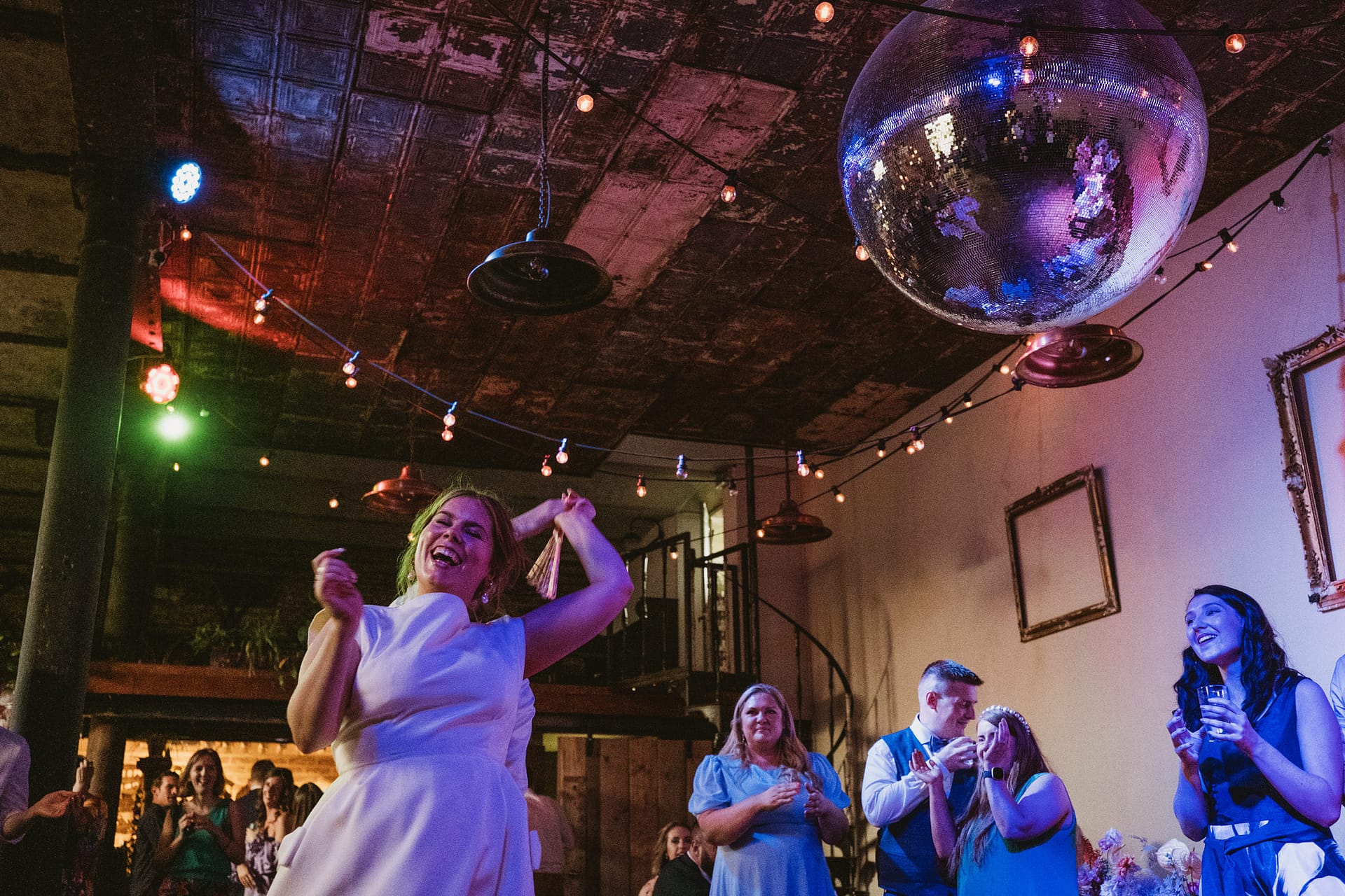 People dancing under disco ball at party.
