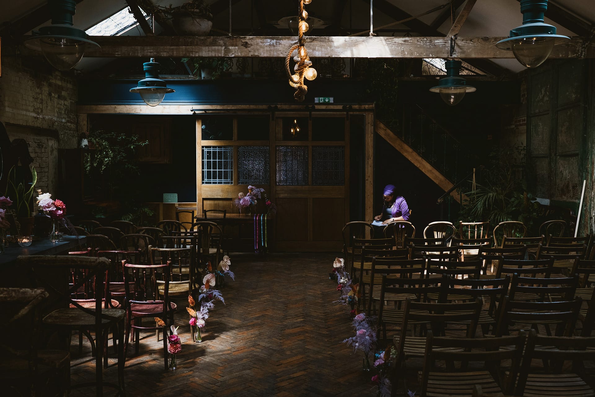 Dimly lit wedding venue with flower aisle.