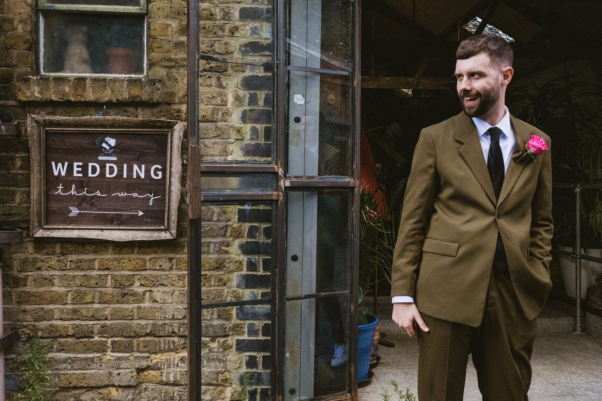 Man in suit near wedding sign on brick wall