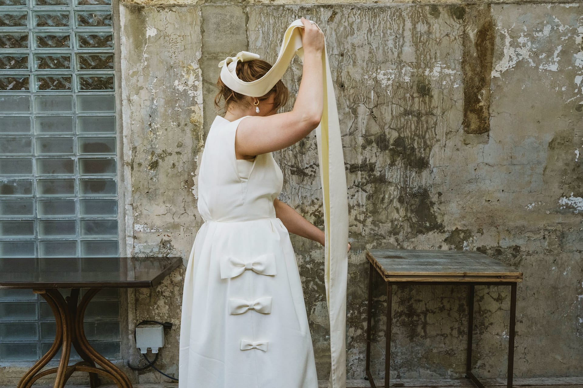Woman in white dress adjusting long ribbon.
