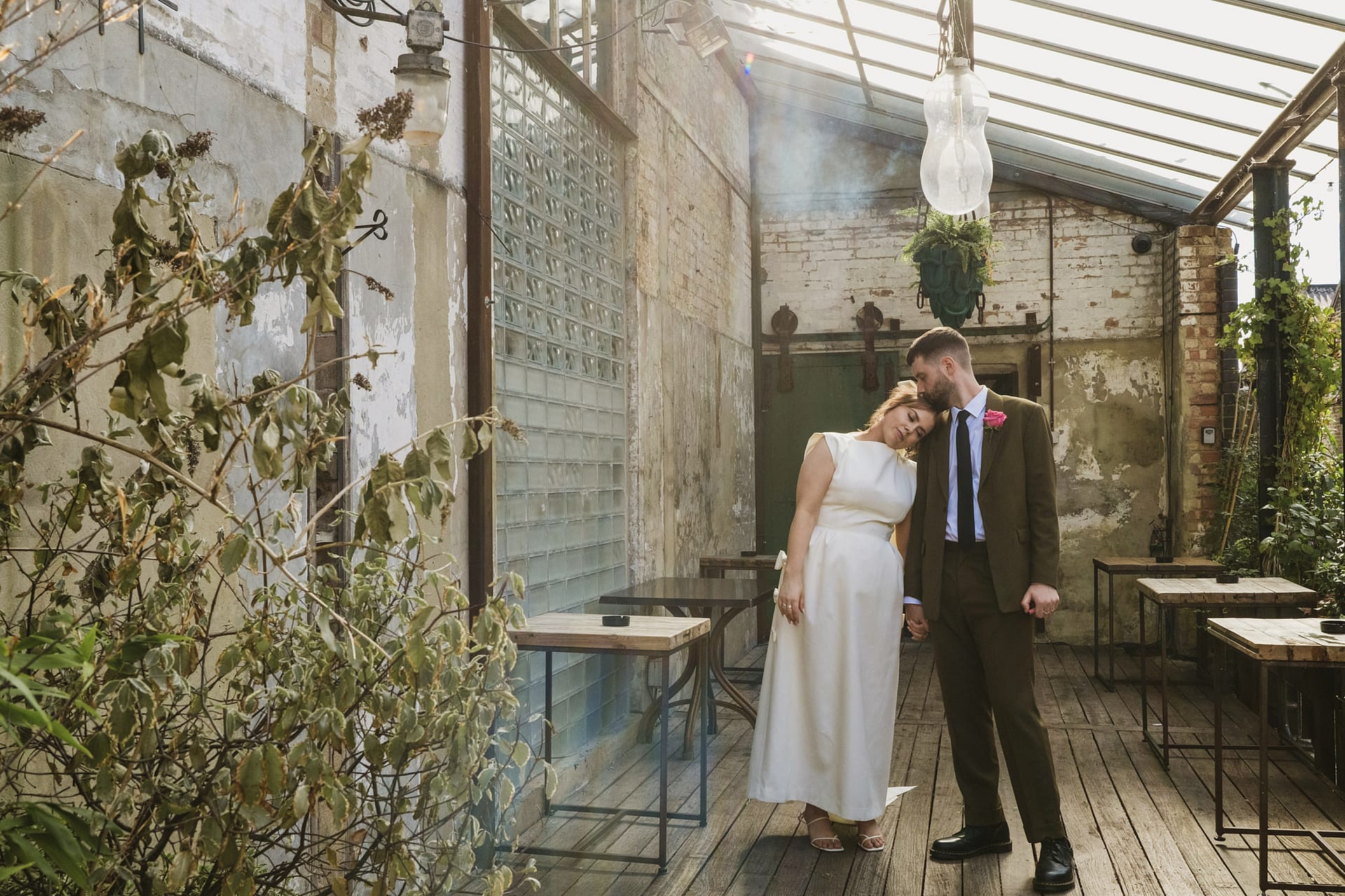 Newlywed couple embracing outside Clapton Country Club in London.