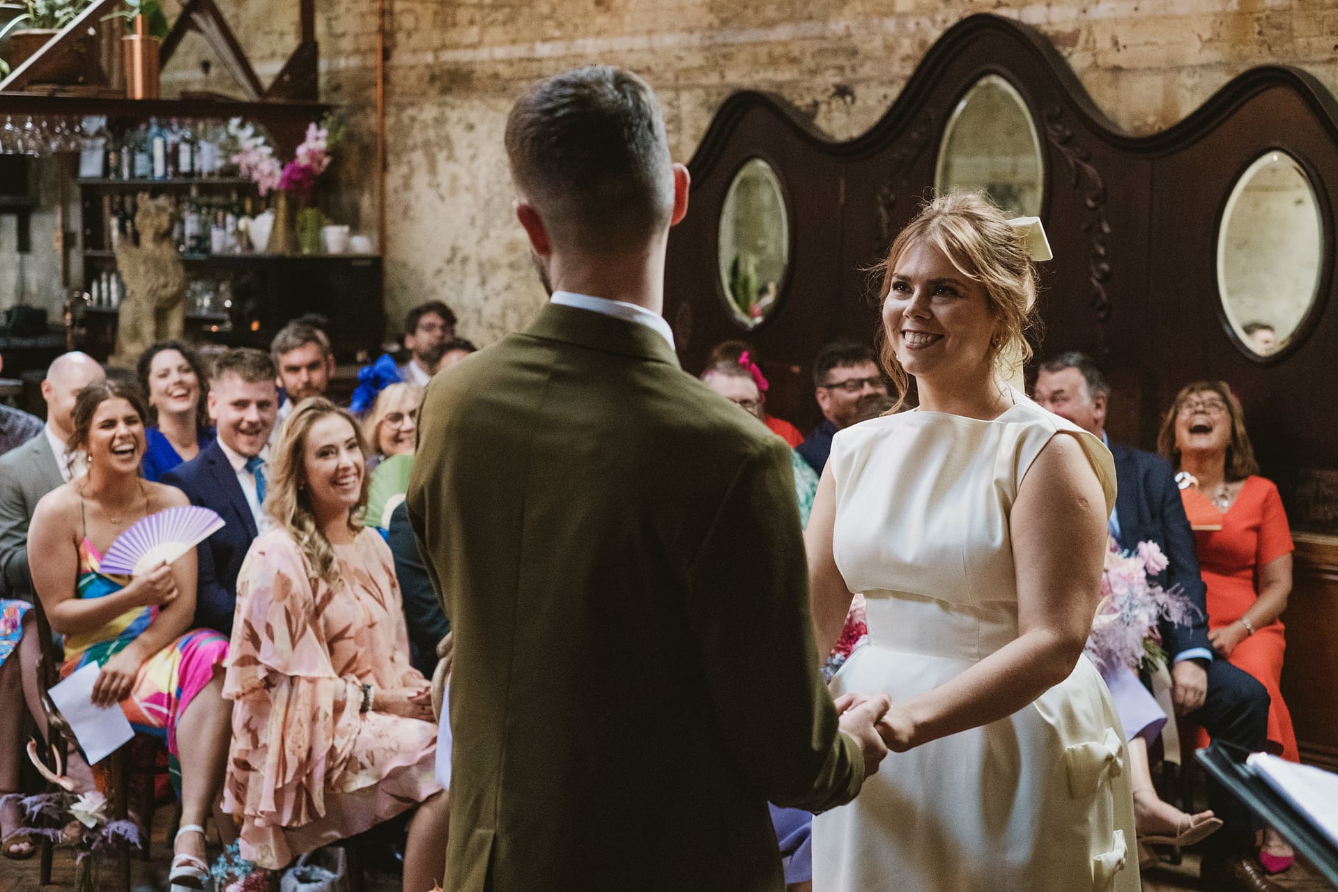 Bride and groom exchanging vows with guests smiling.