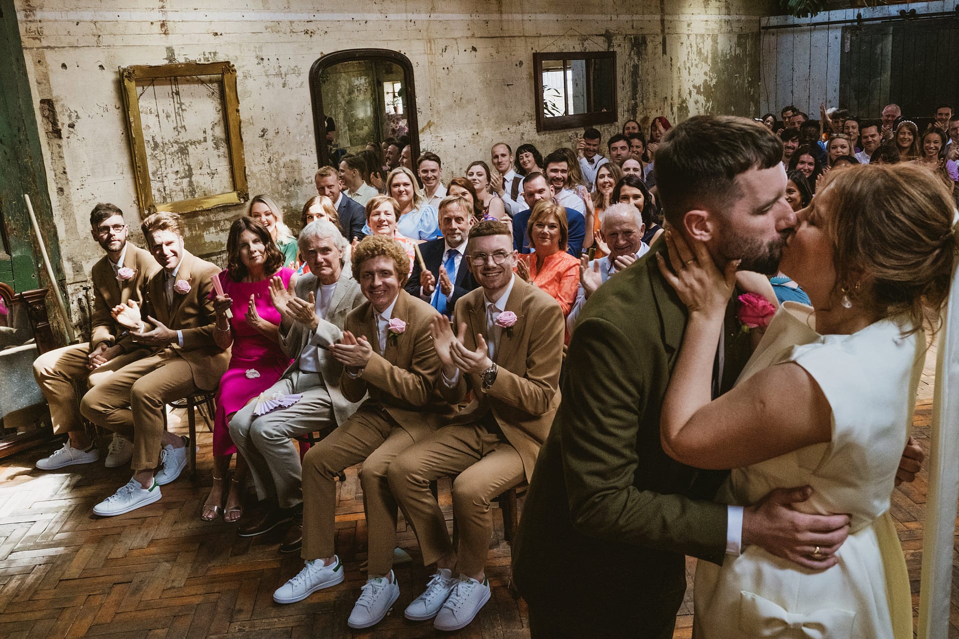 Couple kissing at their wedding at Clapton Country Club, guests clapping.